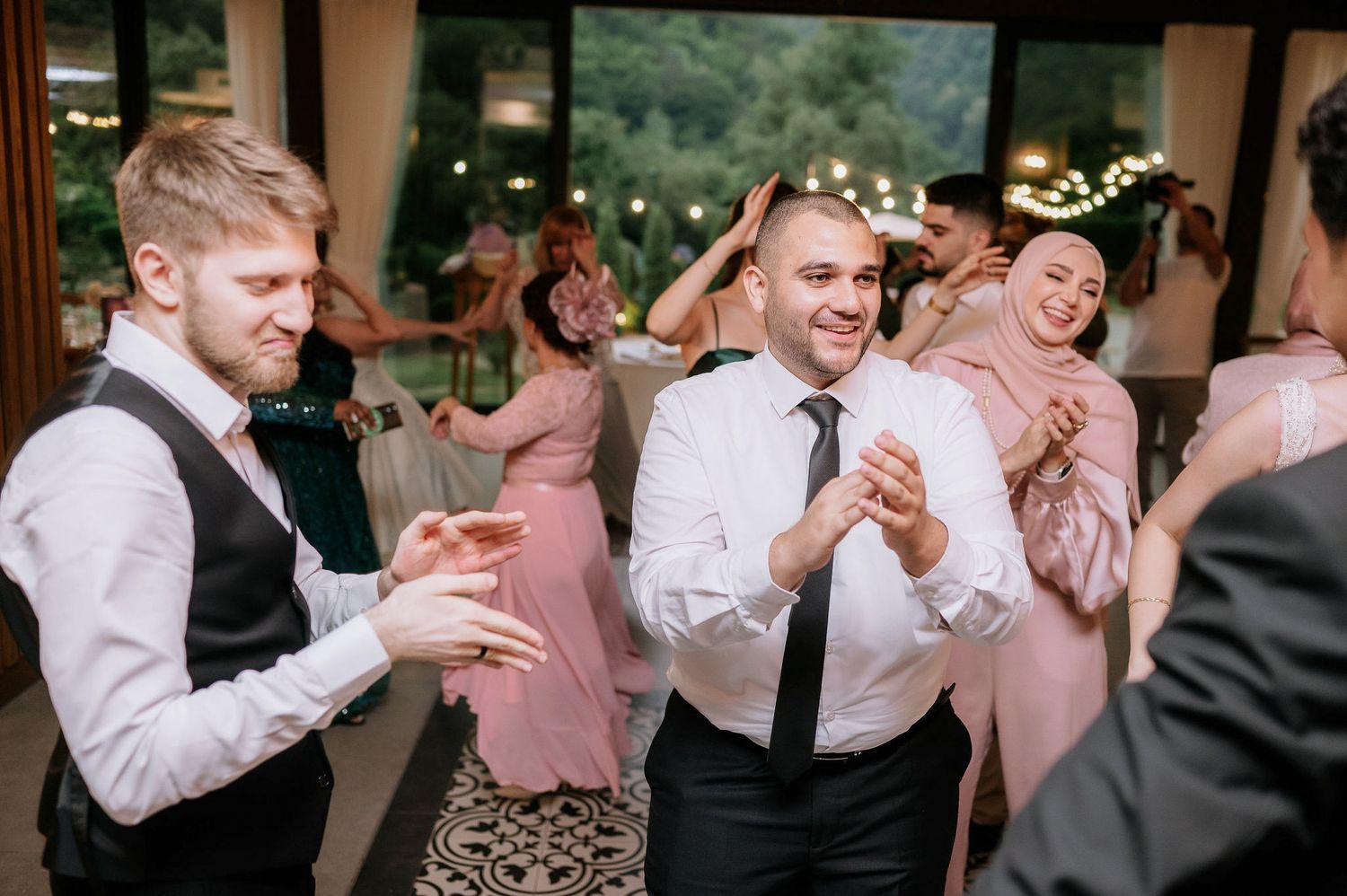 Wedding guests dancing and celebrating joyfully at an indoor reception venue.