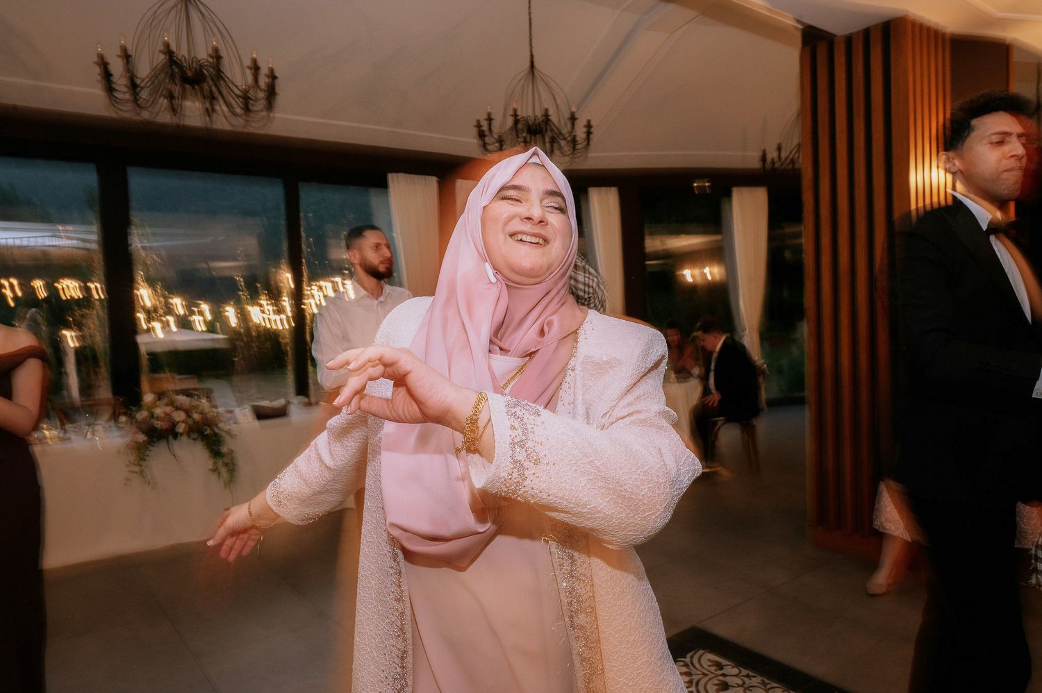 People dancing together in formal attire at an evening wedding reception.