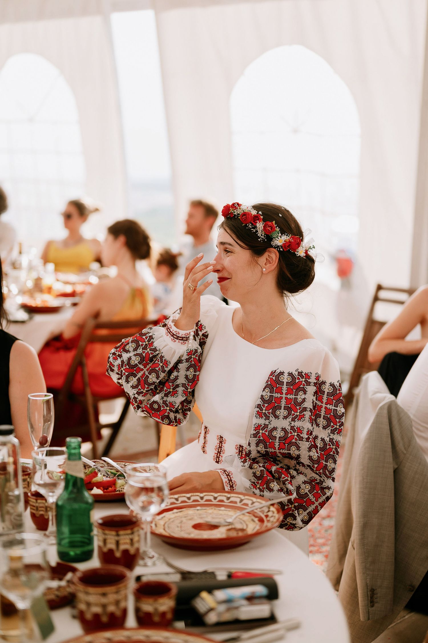 Wedding guests in traditional embroidered attire dining at decorated tables.