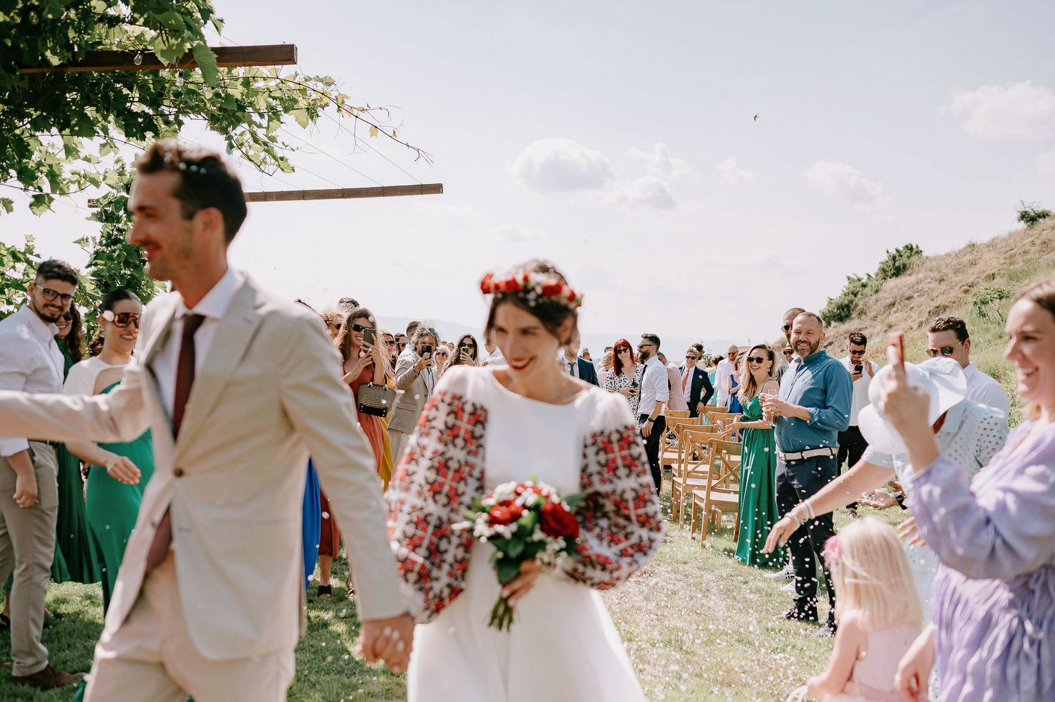 Wedding guests celebrate as the couple exits their outdoor ceremony.