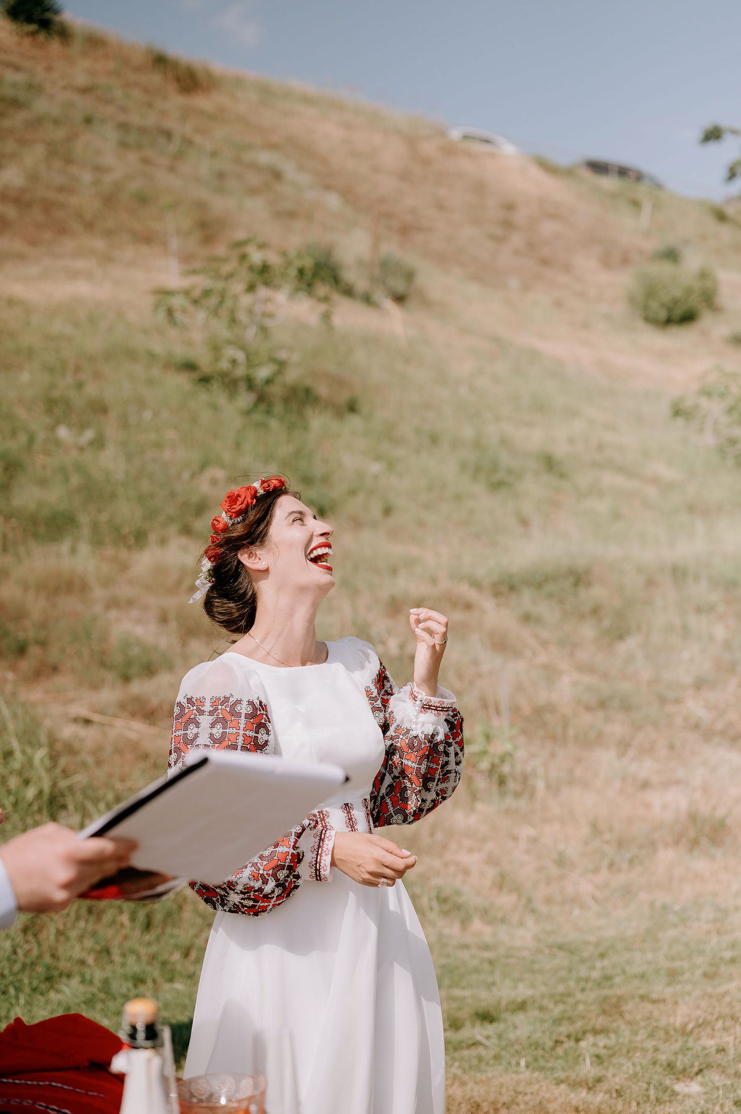 White dress with embroidered sleeves being displayed against hillside background.
