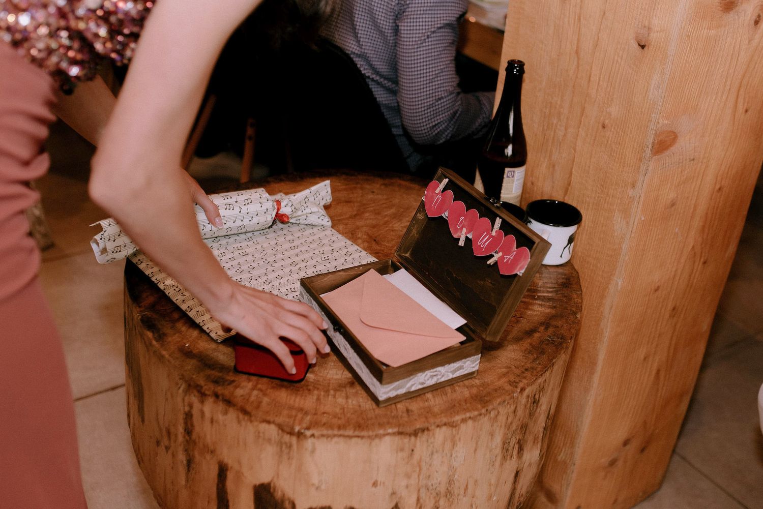 Close up of hands signing documents on rustic wooden surface.