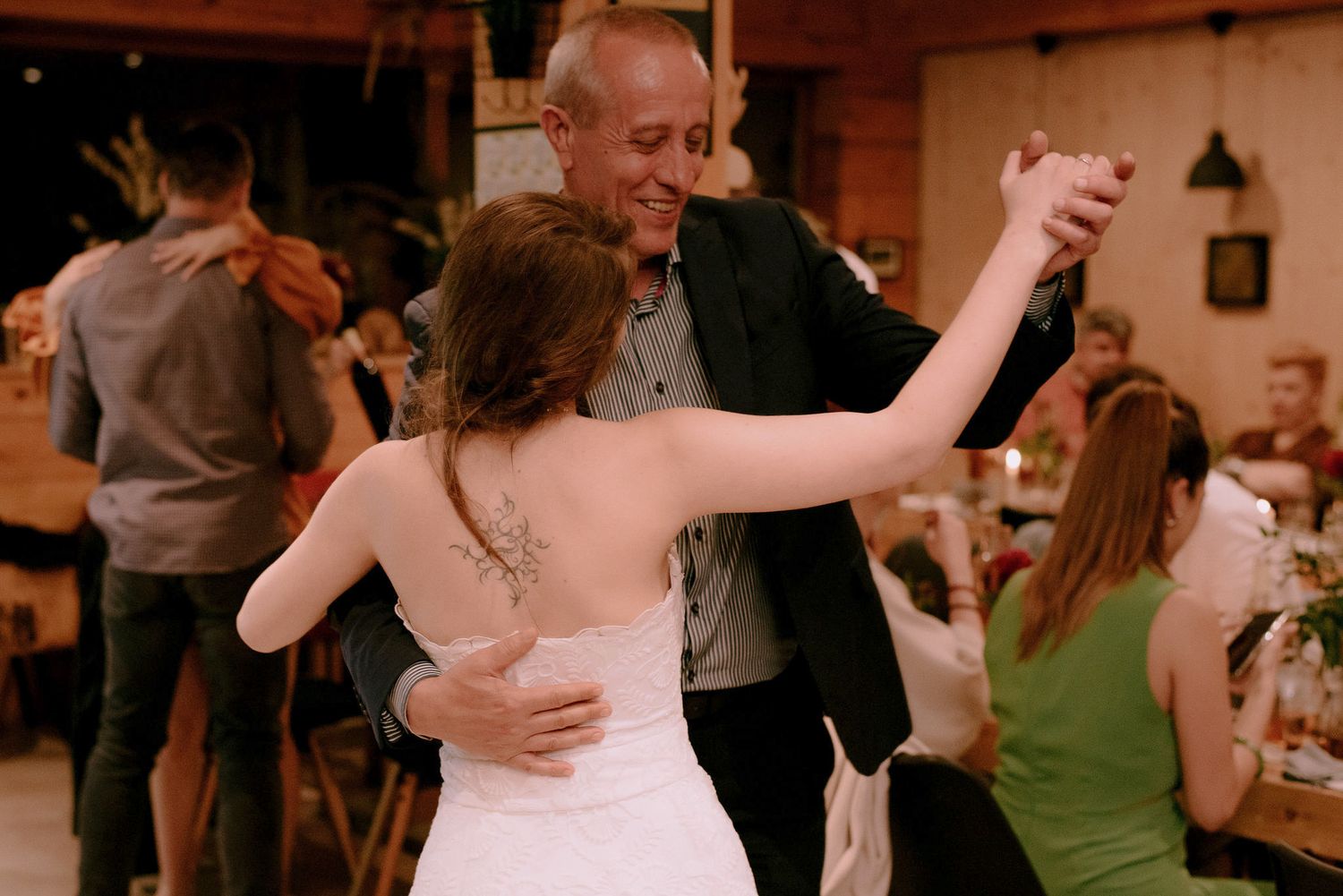 Dancers enjoying themselves at a wedding reception in a warmly lit indoor venue.
