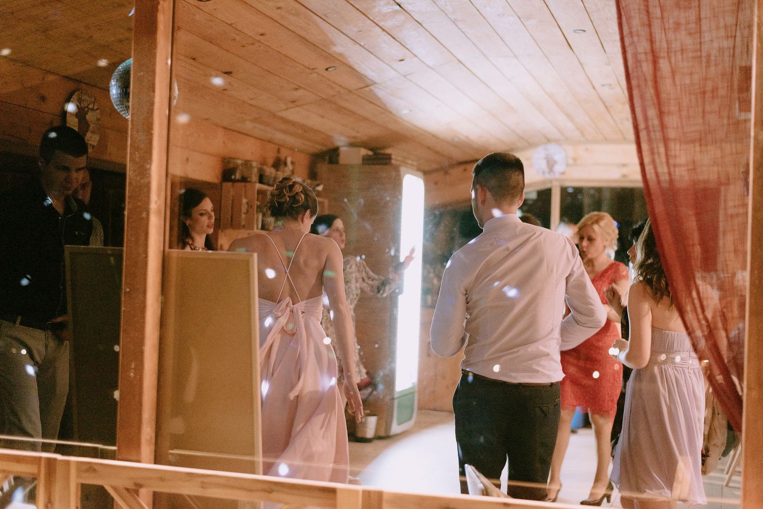 Wedding reception dance floor with guests celebrating under wooden ceiling.