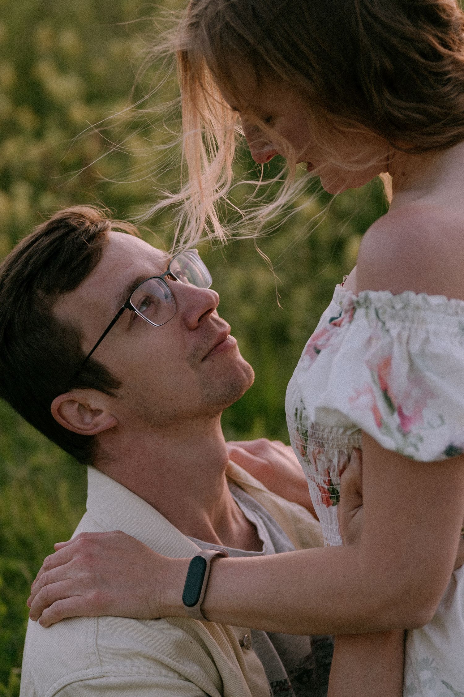 A romantic embrace in a golden field during sunset shows a tender moment between two people.