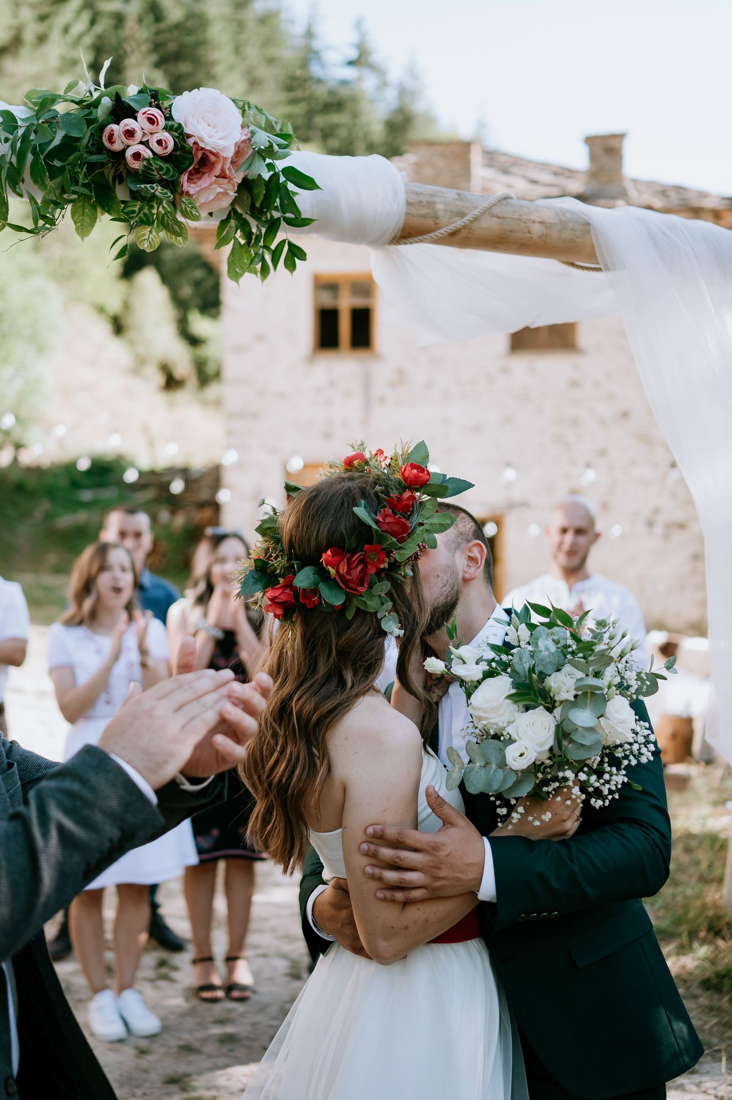 Emotional wedding moment captured in outdoor venue with white curtains and floral decorations.