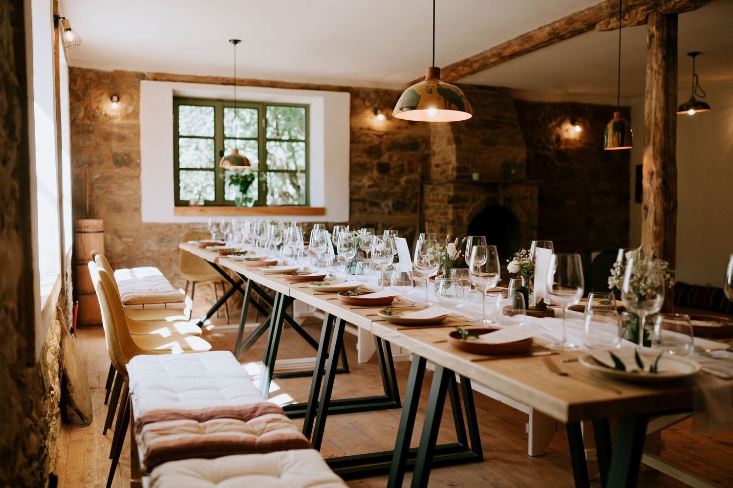 Rustic dining room with stone walls and long wooden table set for formal dinner.