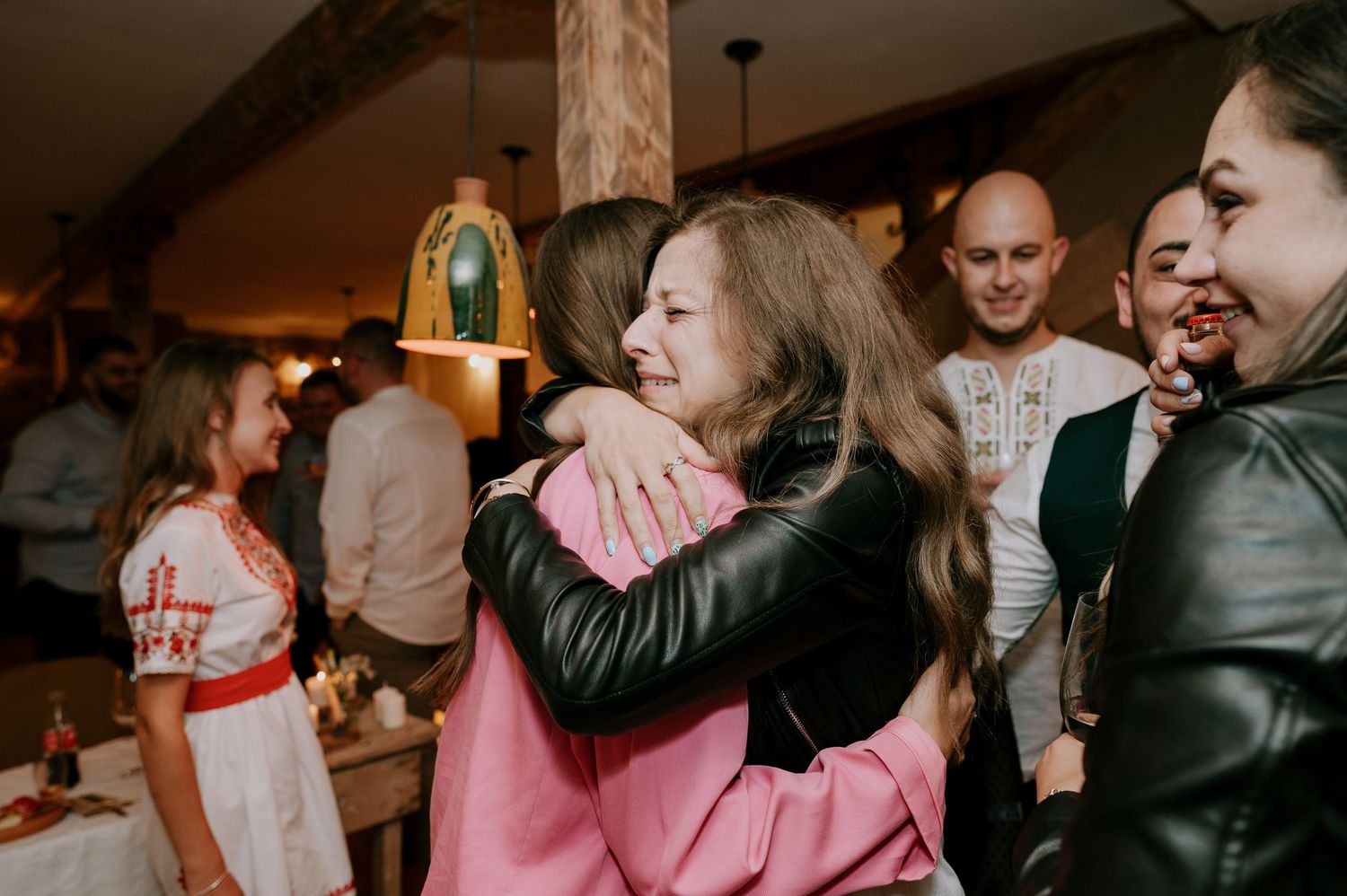 Friends sharing emotional embraces during a celebration indoors.