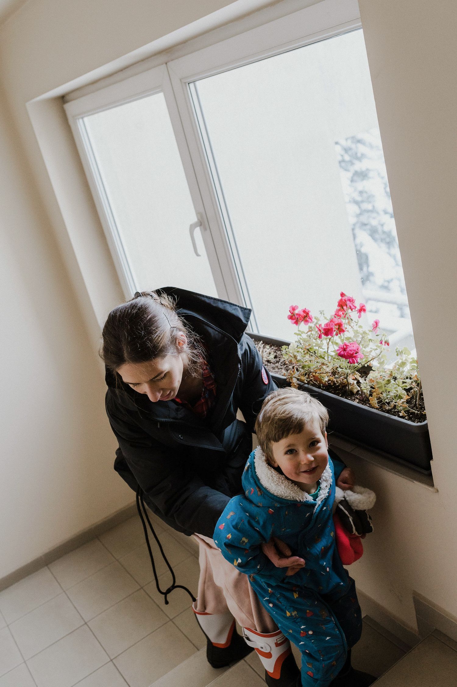 Parent and child look out window together in sequence of candid black and white photographs.