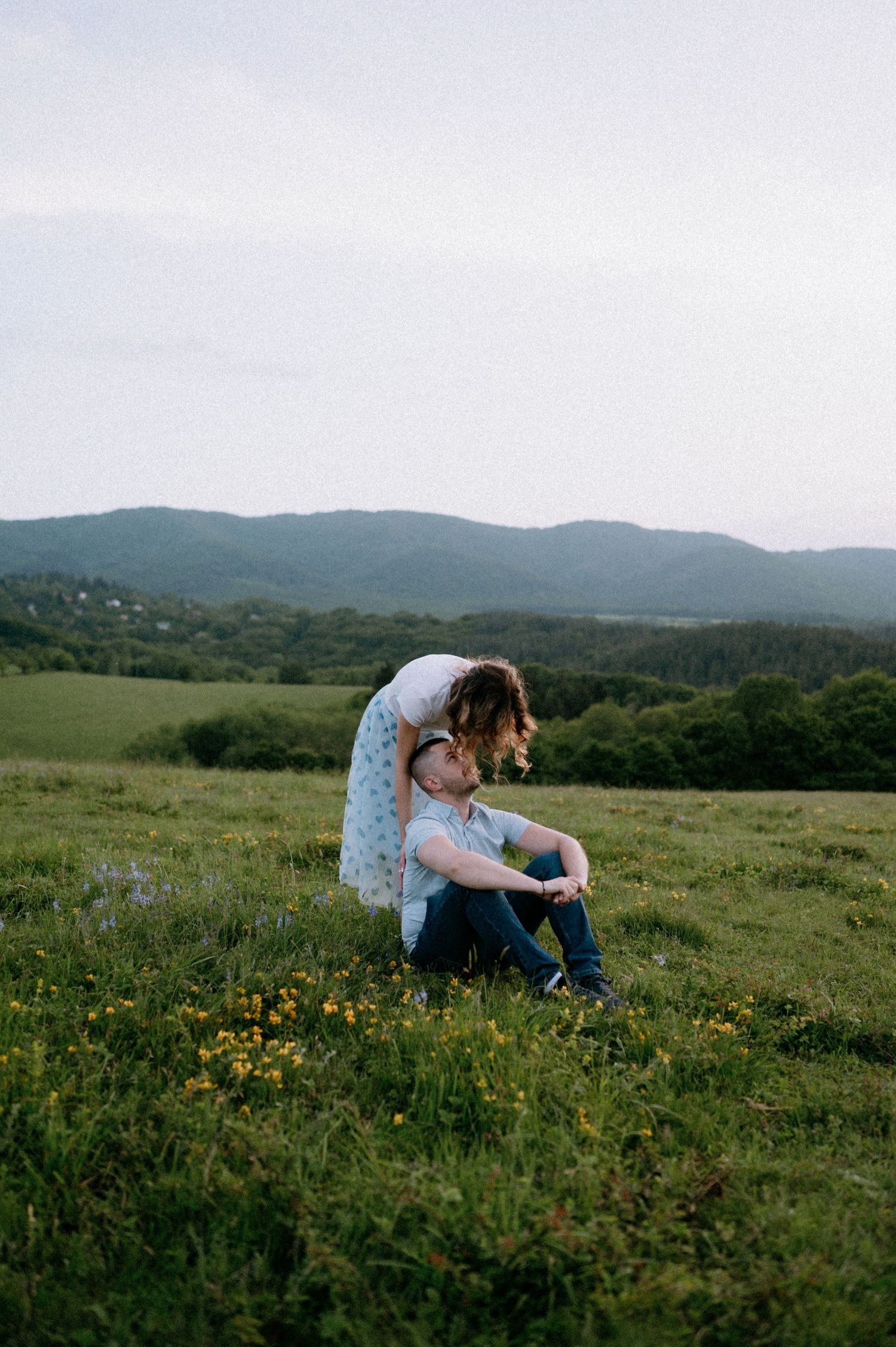 An intimate moment between two people in a mountain meadow filled with yellow flowers.