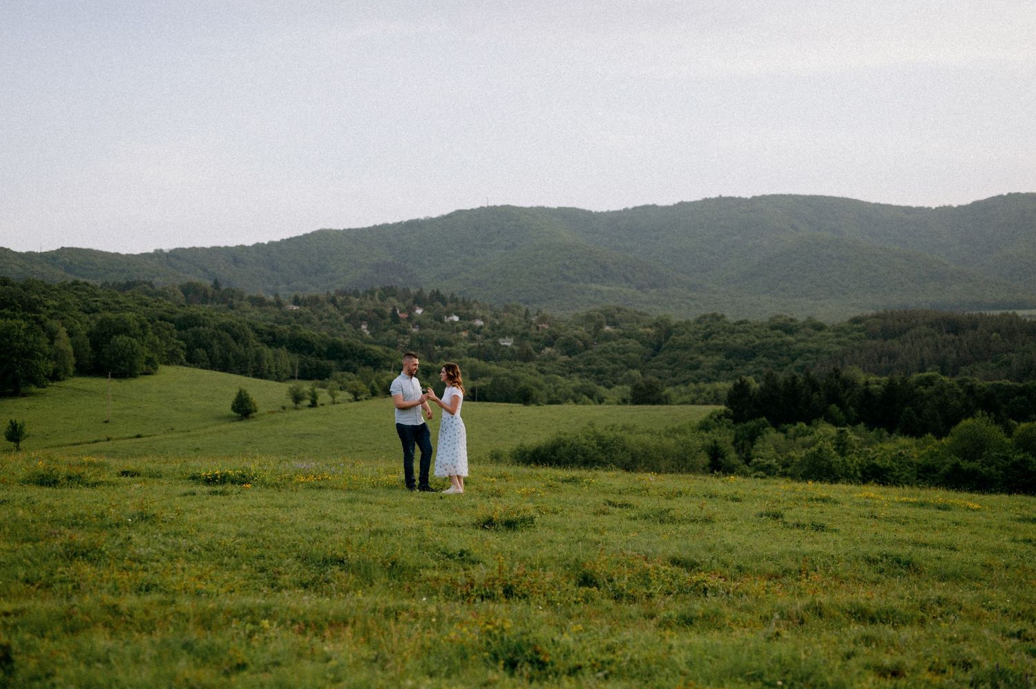 Sweeping mountain landscape with green fields and distant figures on the hillside.
