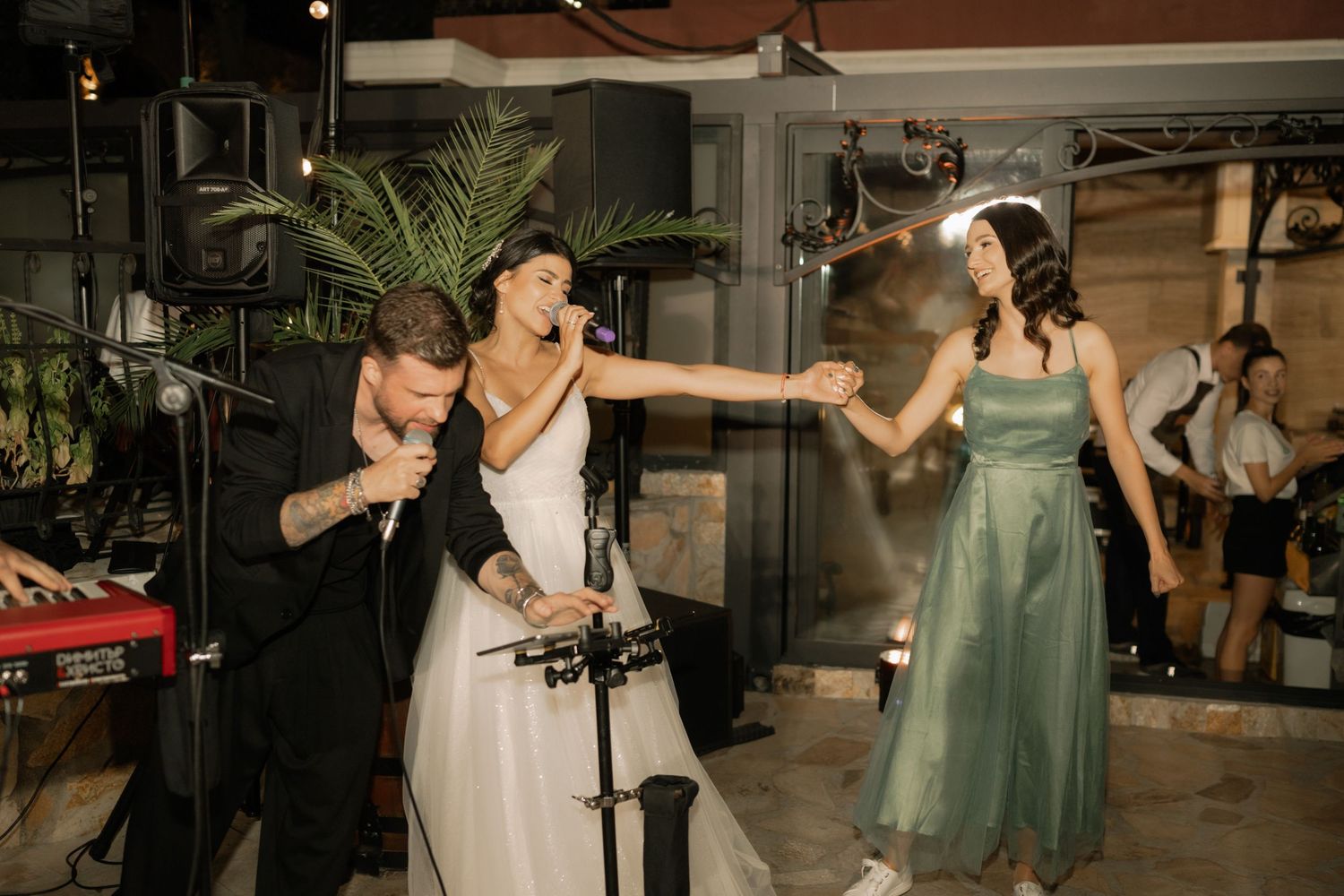 Wedding guests dance and celebrate at a lively reception with a tropical palm decor setting.