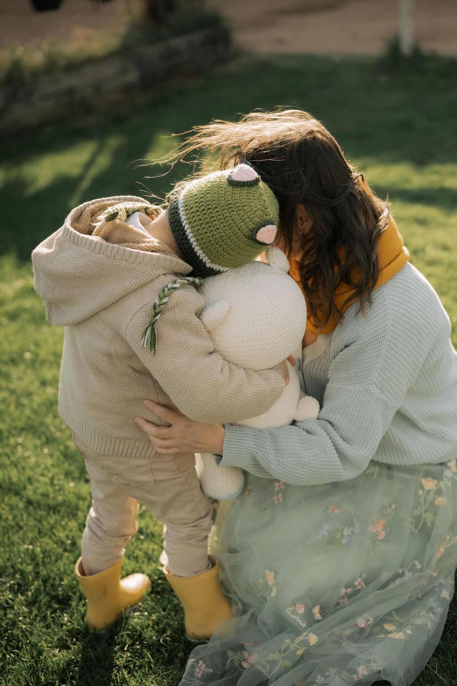 A sequence of photos showing someone in a cream hoodie and mint sweater bending down in a grassy outdoor setting.