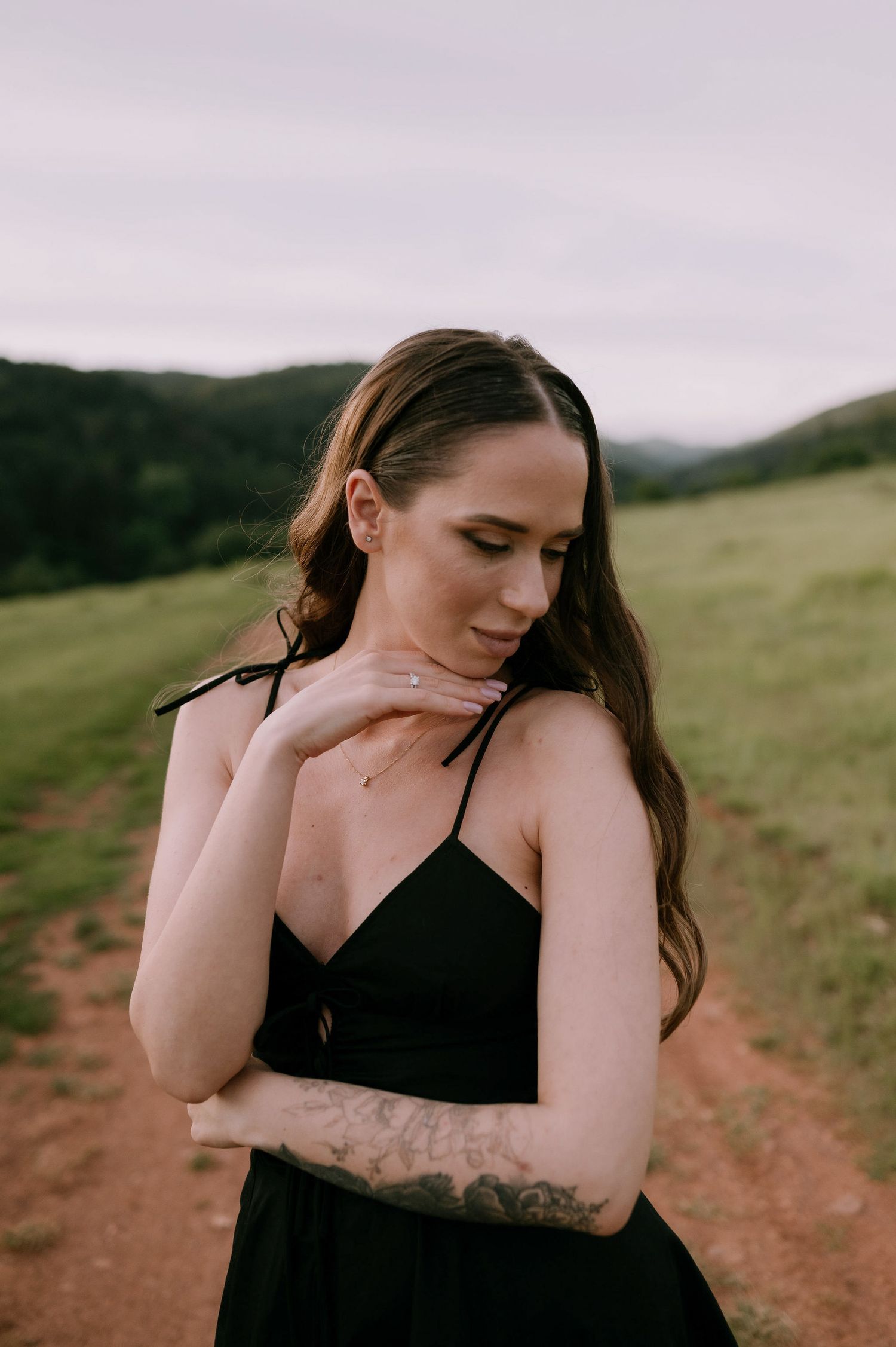A series of artistic portraits showing a person in black against a natural outdoor backdrop with rolling hills.