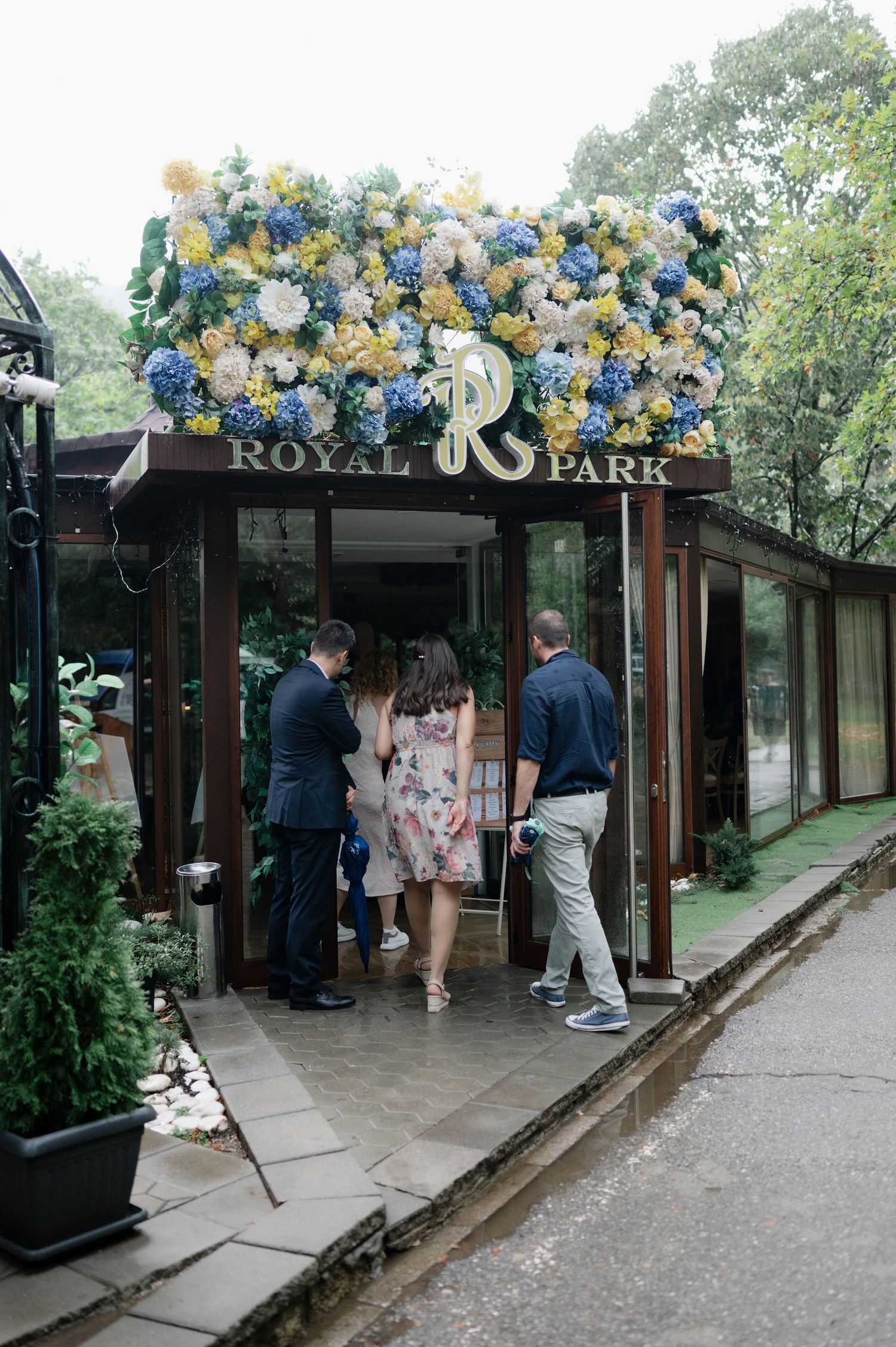 Visitors gather at the entrance of Royal Park decorated with blue and gold balloons and signage.