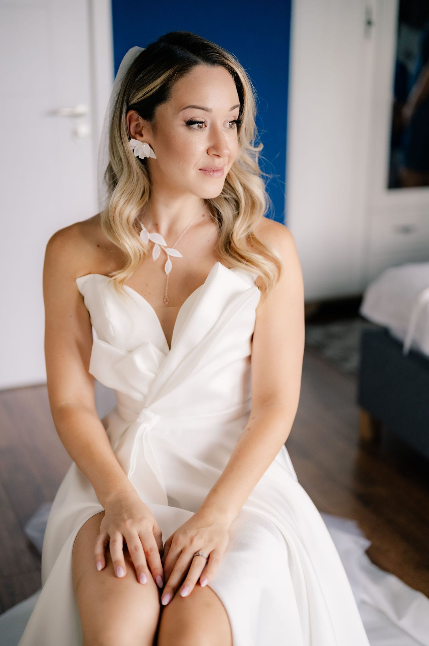 A series of four elegant bridal boudoir photos showing a person in a white dress sitting on a bed in natural light.