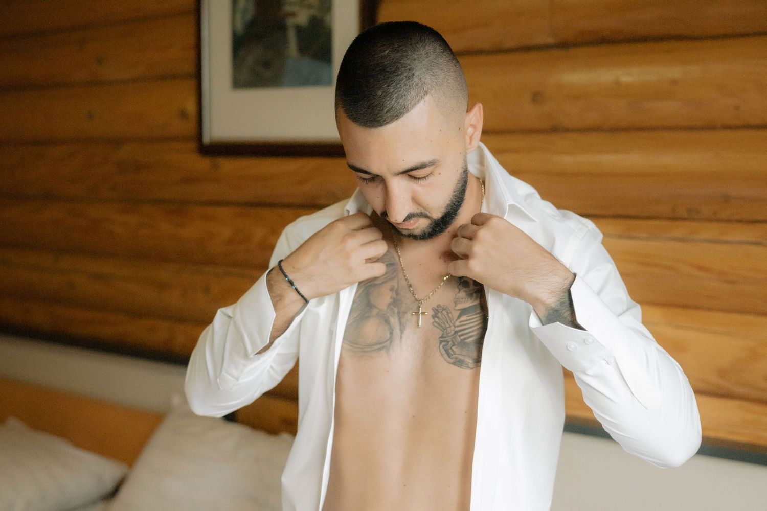 Person in white dress shirt getting ready in front of rustic wooden wall interior.