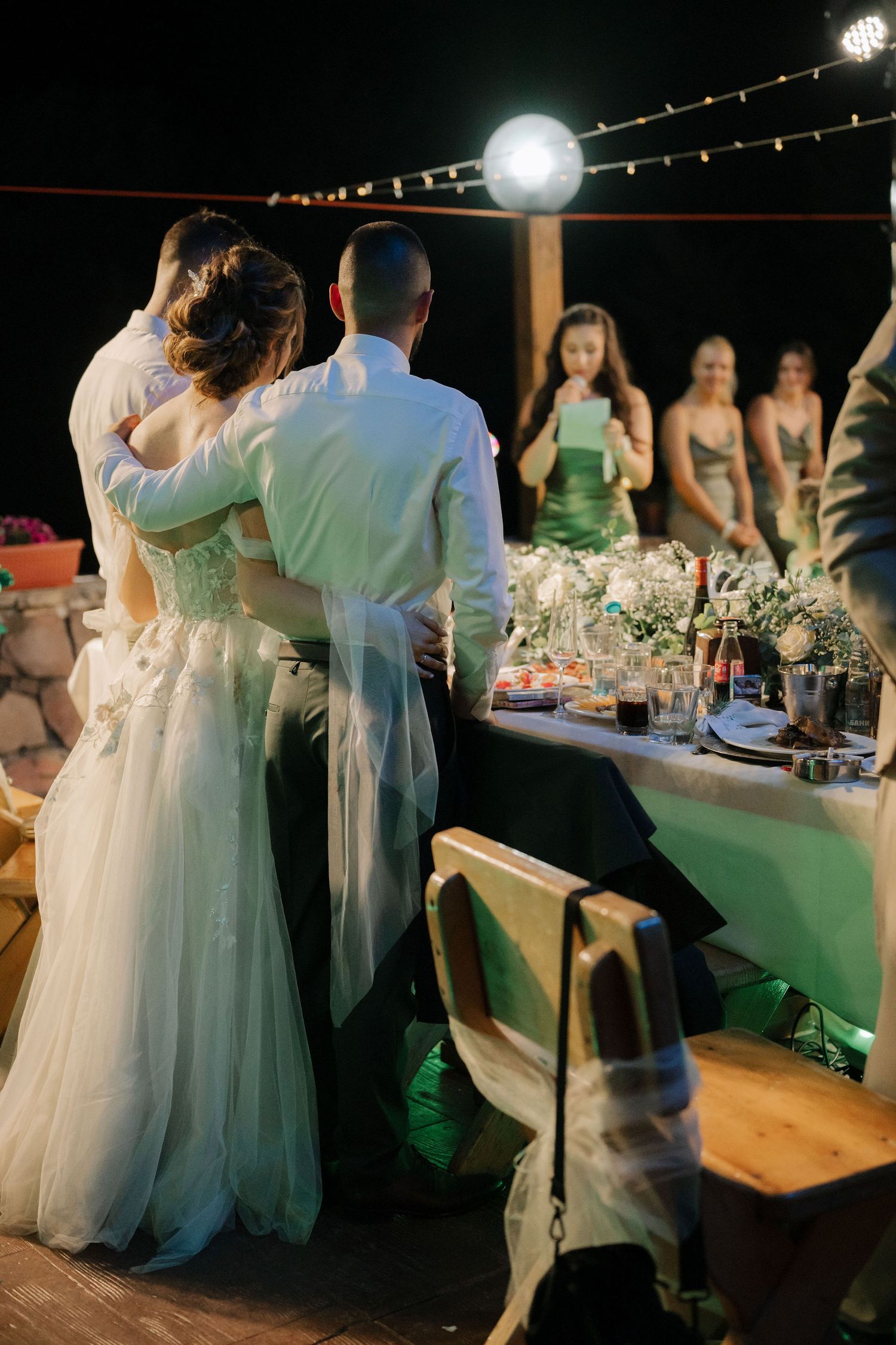 A wedding reception at night with dancing couples and string lights creating a romantic outdoor atmosphere.