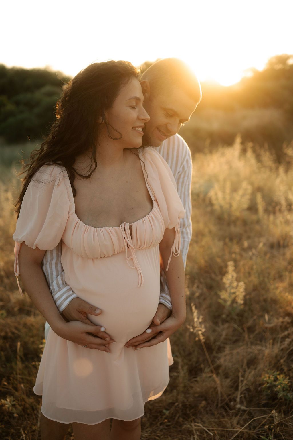 An intimate sunset maternity session showing tender moments between expectant parents in a natural outdoor setting.