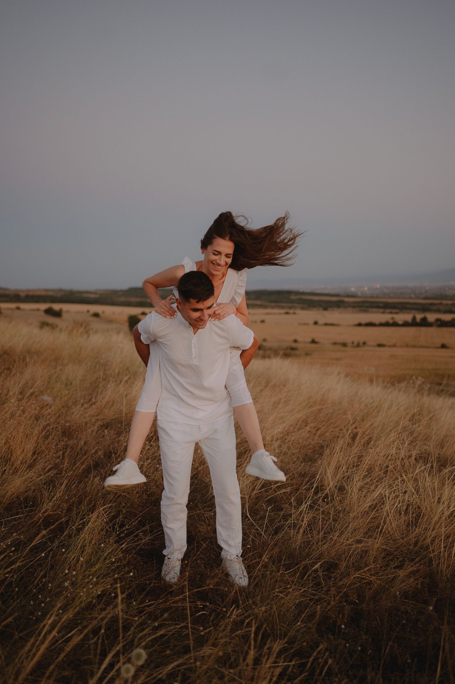 A person in white clothing dances and spins joyfully in a golden field at sunset.