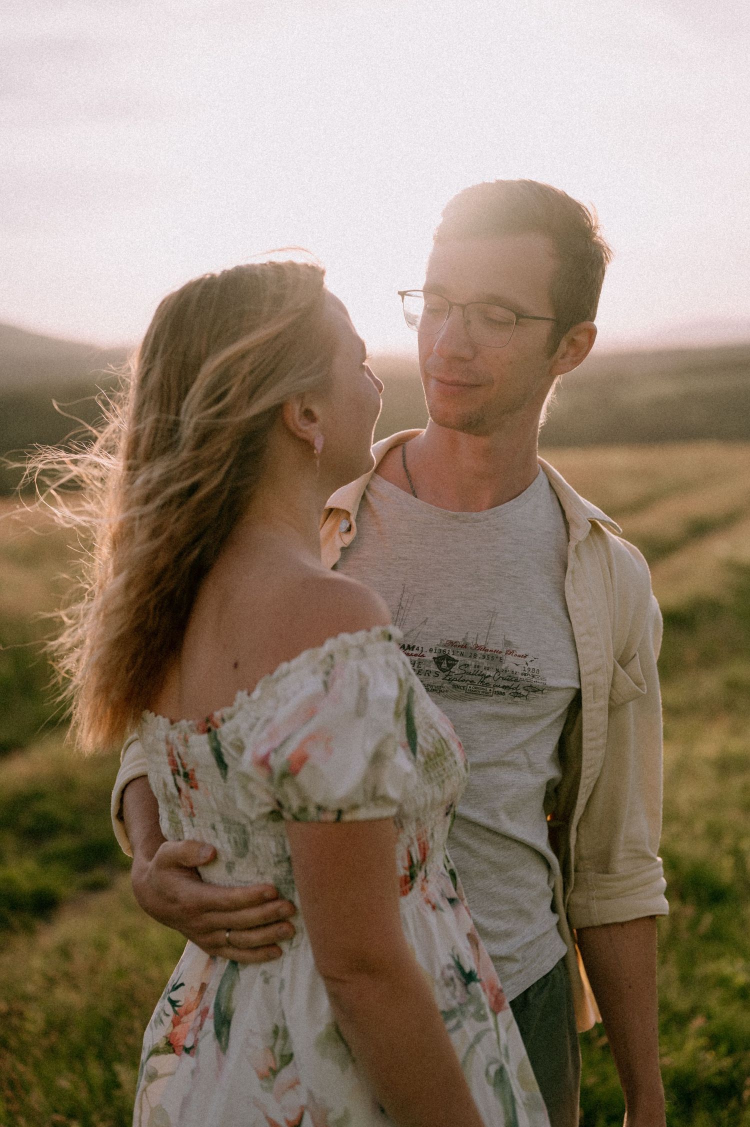 Loving couple sharing tender moments in a sunlit mountain field.