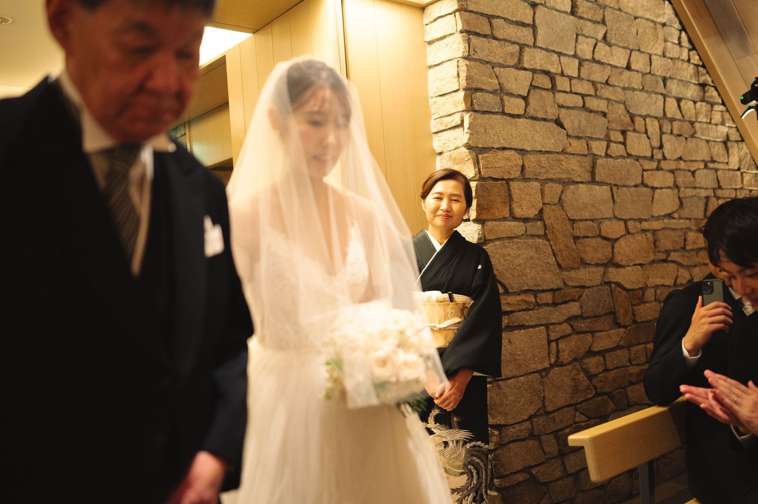 Wedding ceremony in a modern chapel with stone walls and warm lighting.