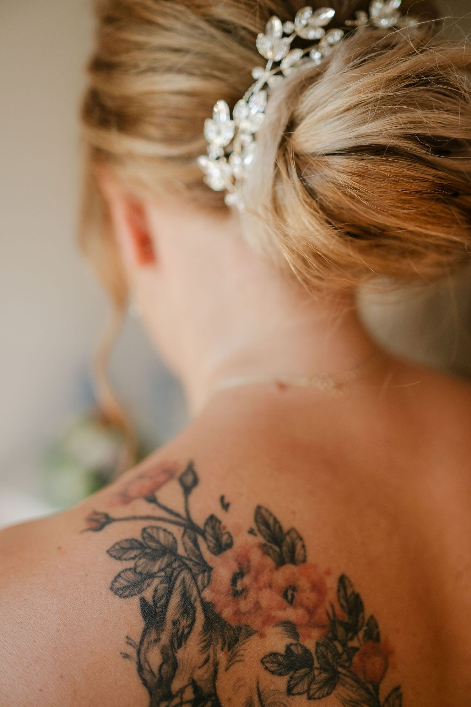 Close-up of floral tattoo artwork and pearl hair accessory on bare shoulder.