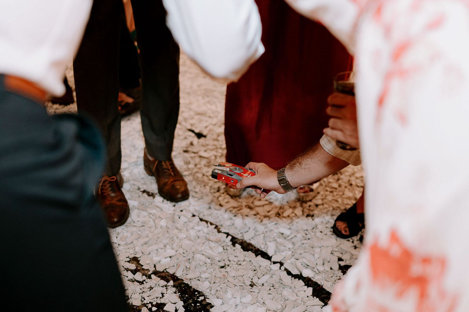 Wedding guests dancing on a rustic floor during evening reception celebrations.