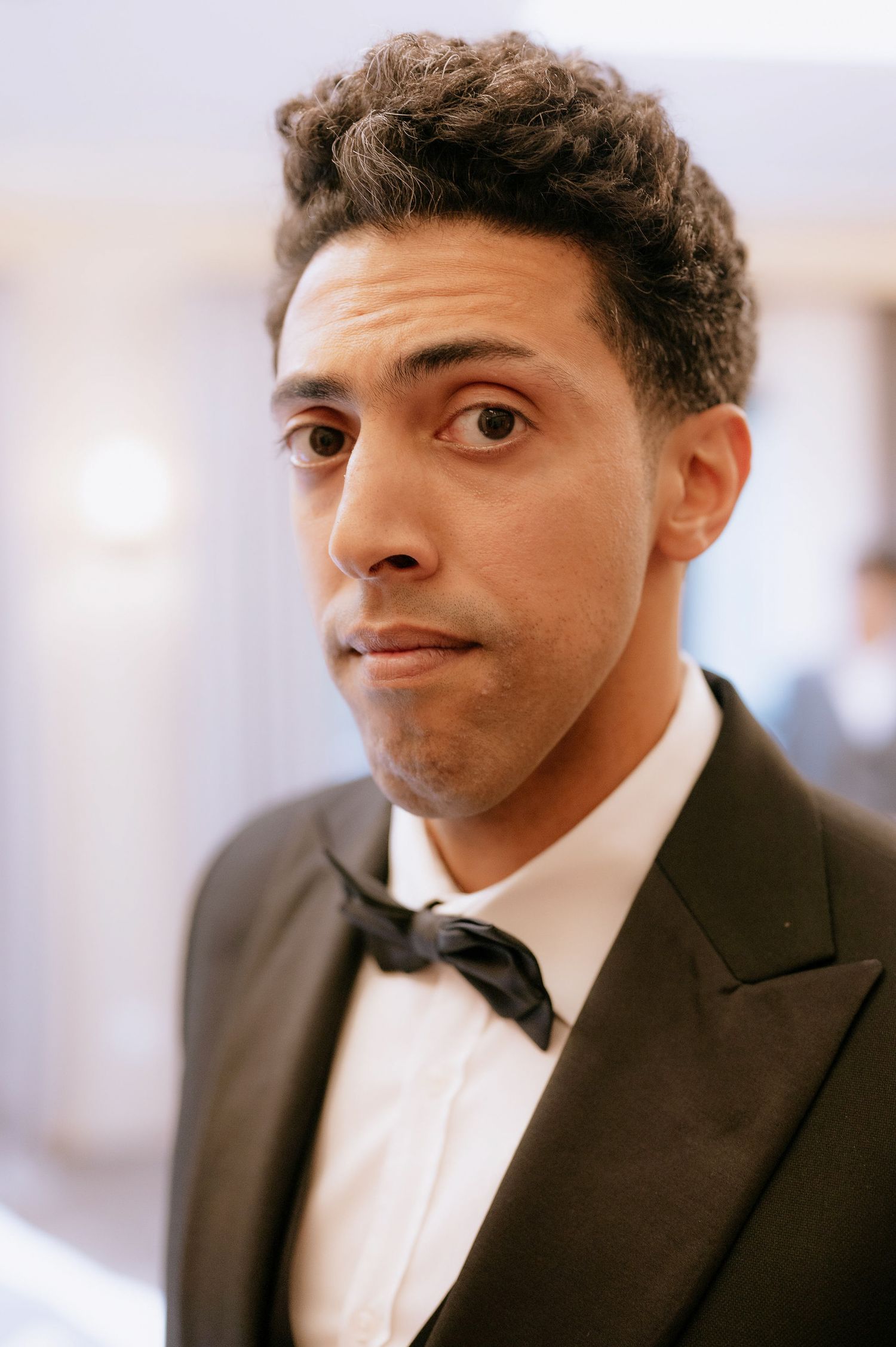 Close-up portrait of someone wearing a black bow tie and formal suit.