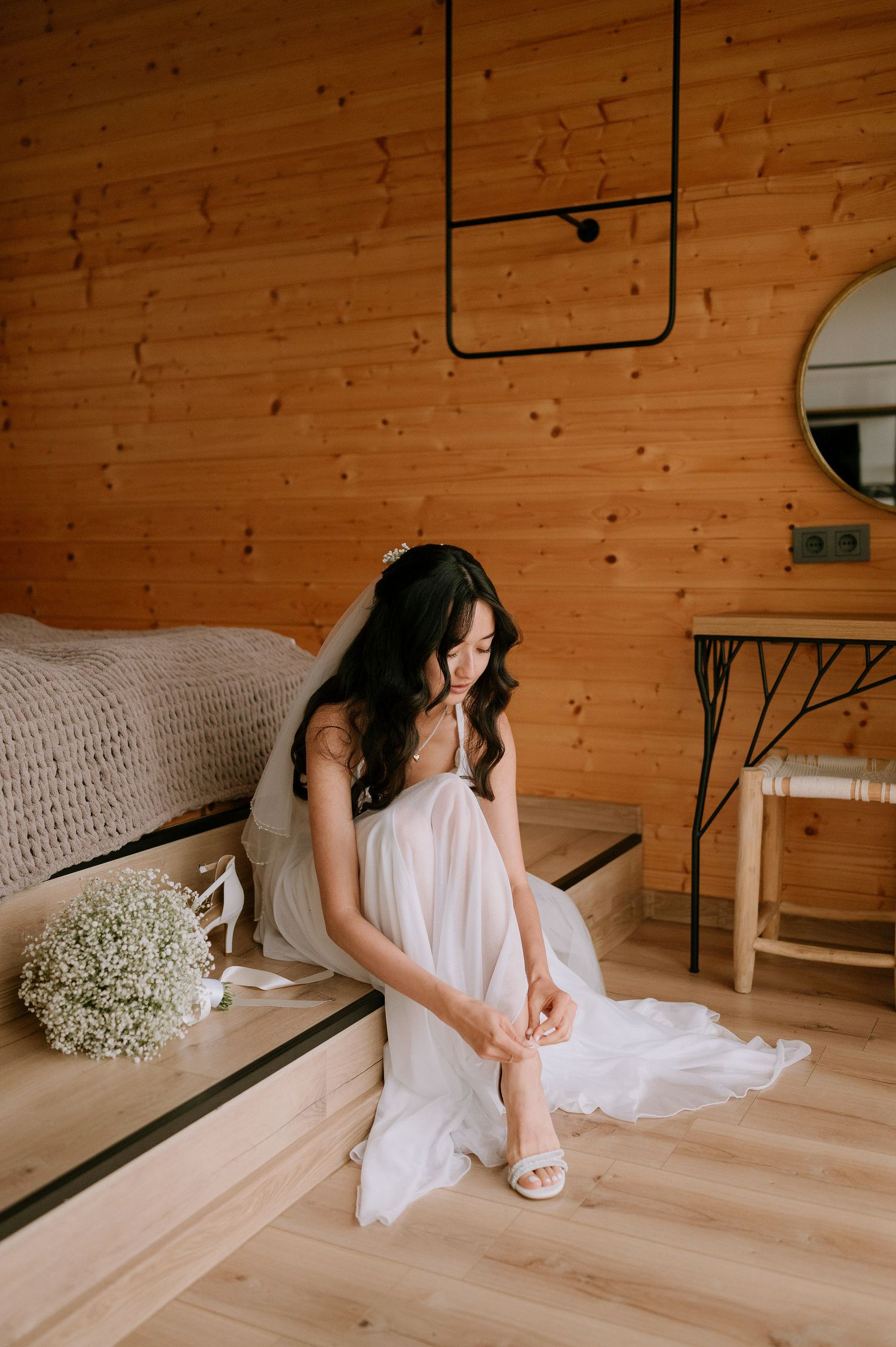 Bridal details in a rustic wooden room with baby's breath flowers and white dress.