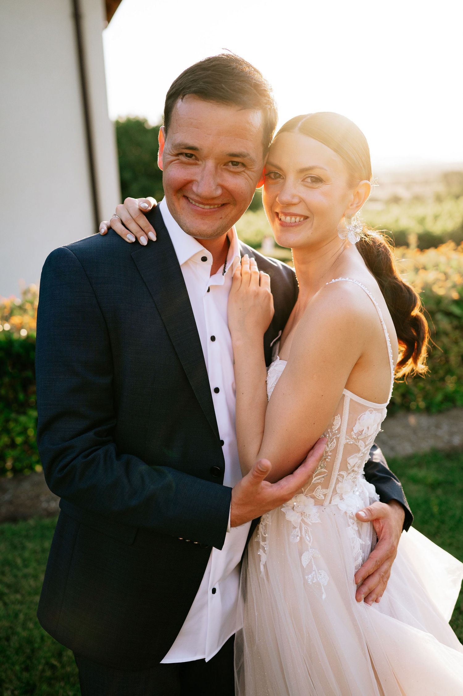Joyful wedding couple embraces during sunset portrait session.