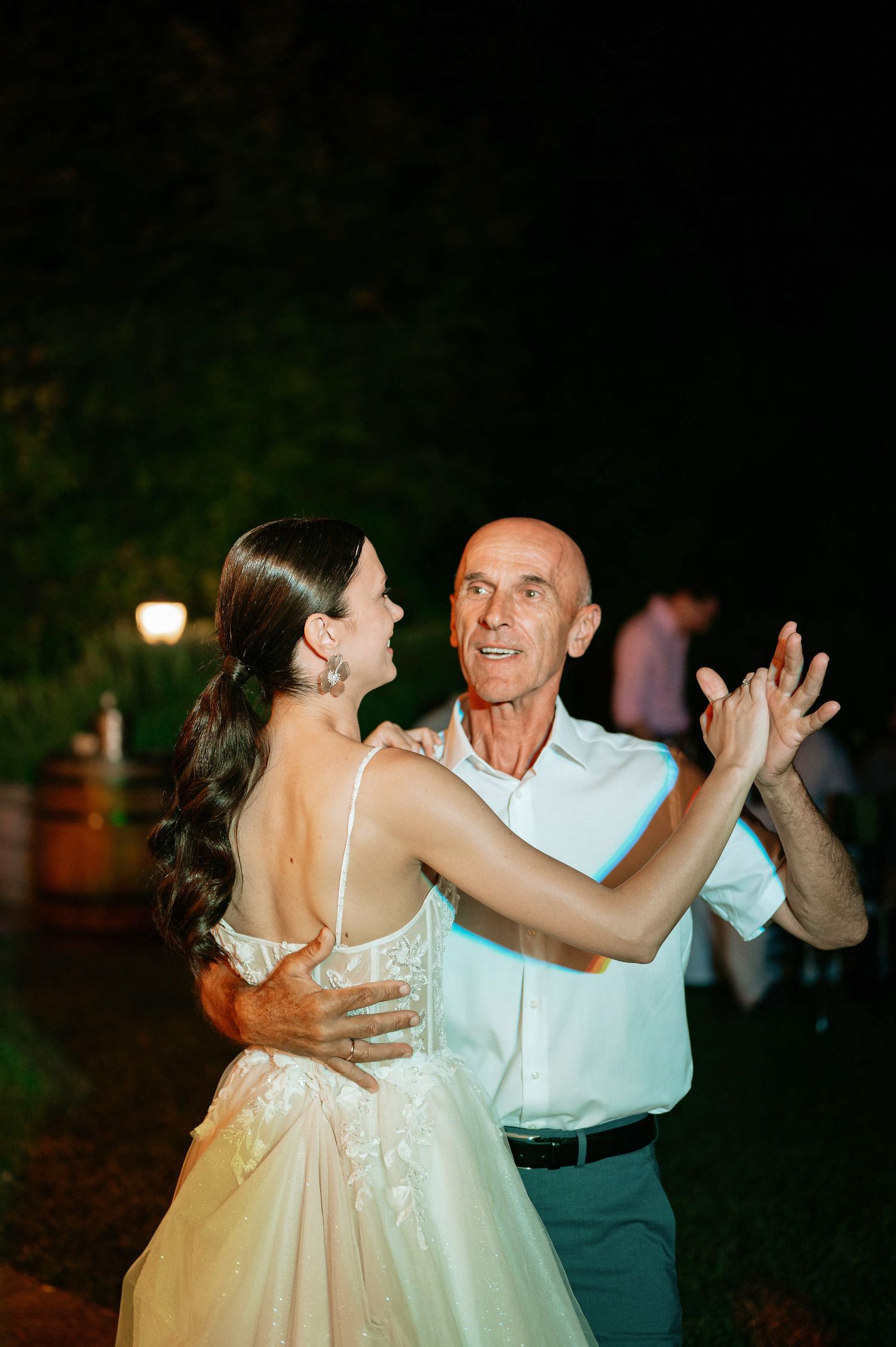 Dancers twirl across the outdoor reception space in formal attire under evening lights.