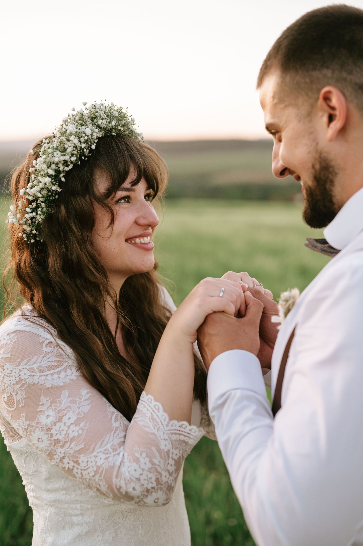 A tender moment between newlyweds in a sunlit meadow.