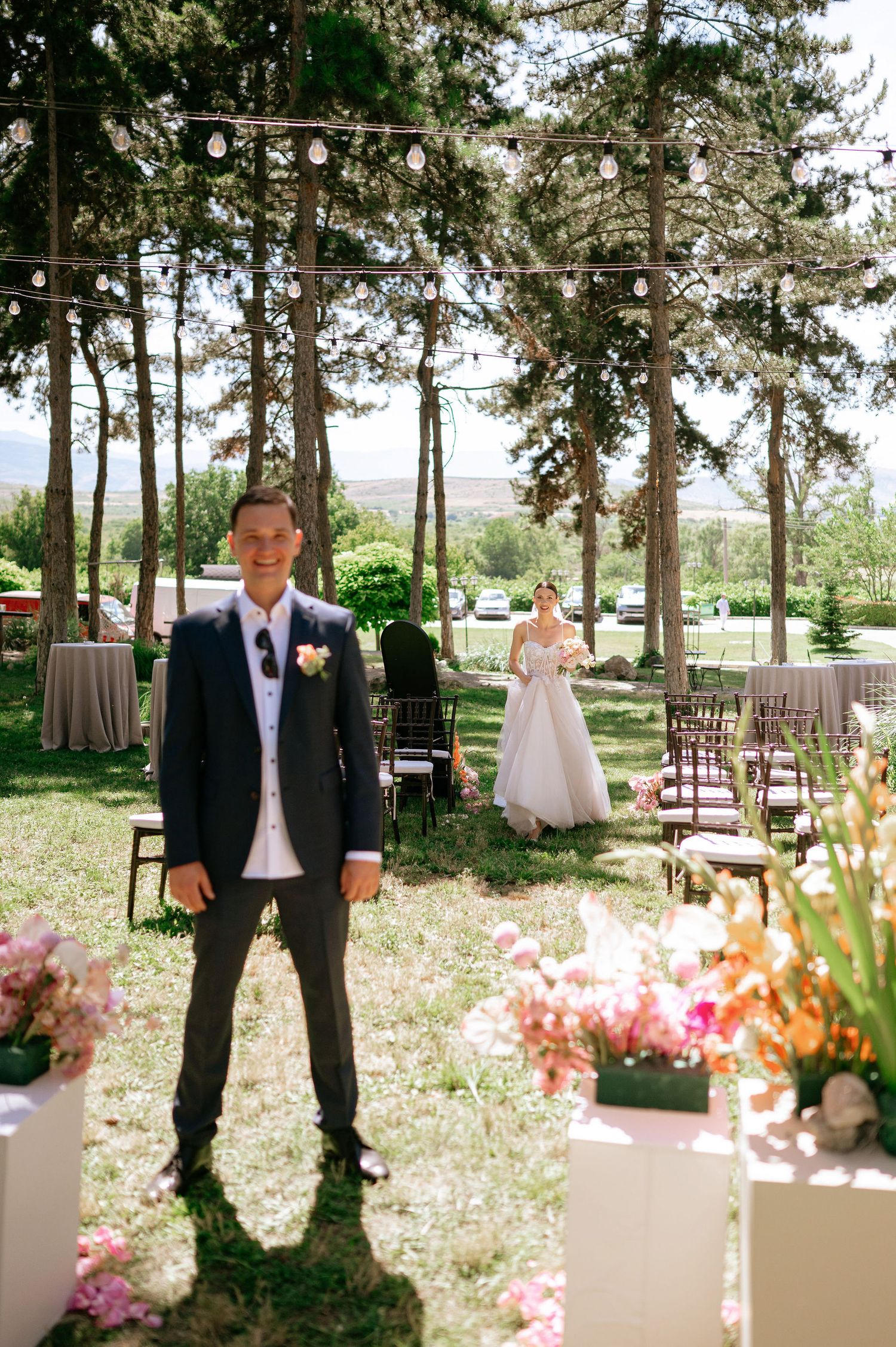 Wedding ceremony setup in a pine forest with floral decorations and wooden chairs.