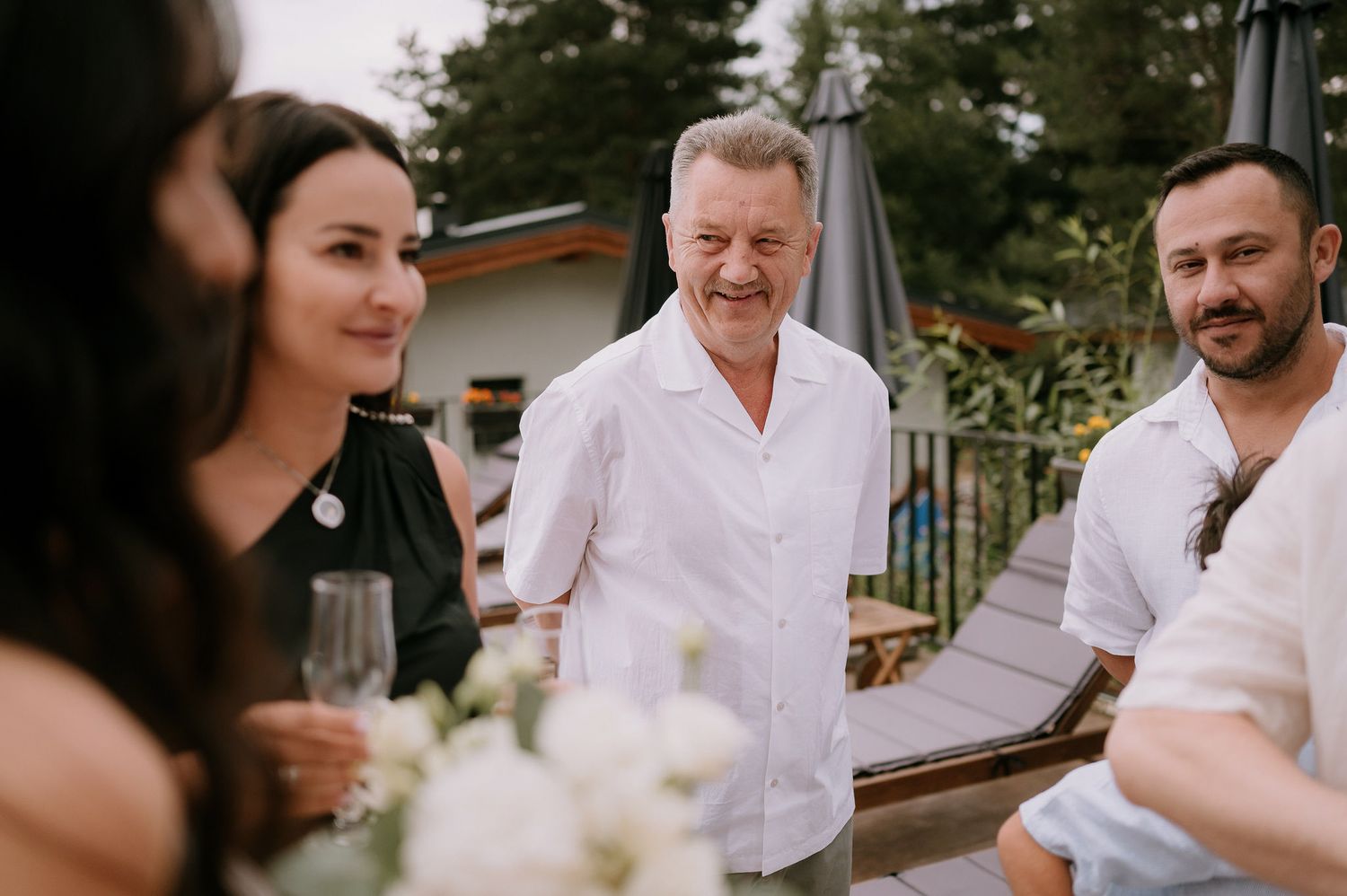 Wedding guests in white attire enjoying celebratory moments at an outdoor venue.