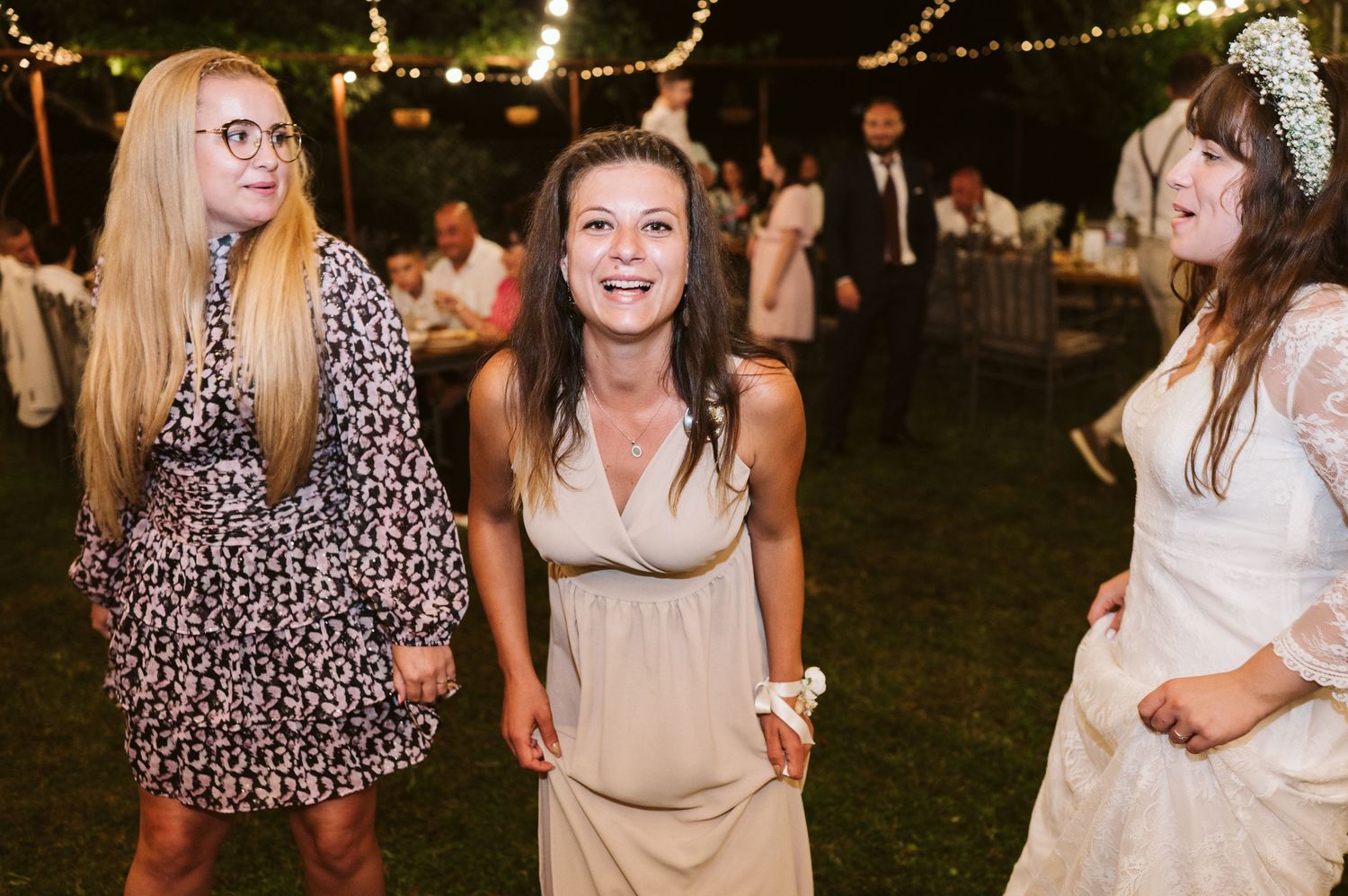 Wedding guests dancing and celebrating at an outdoor evening reception.
