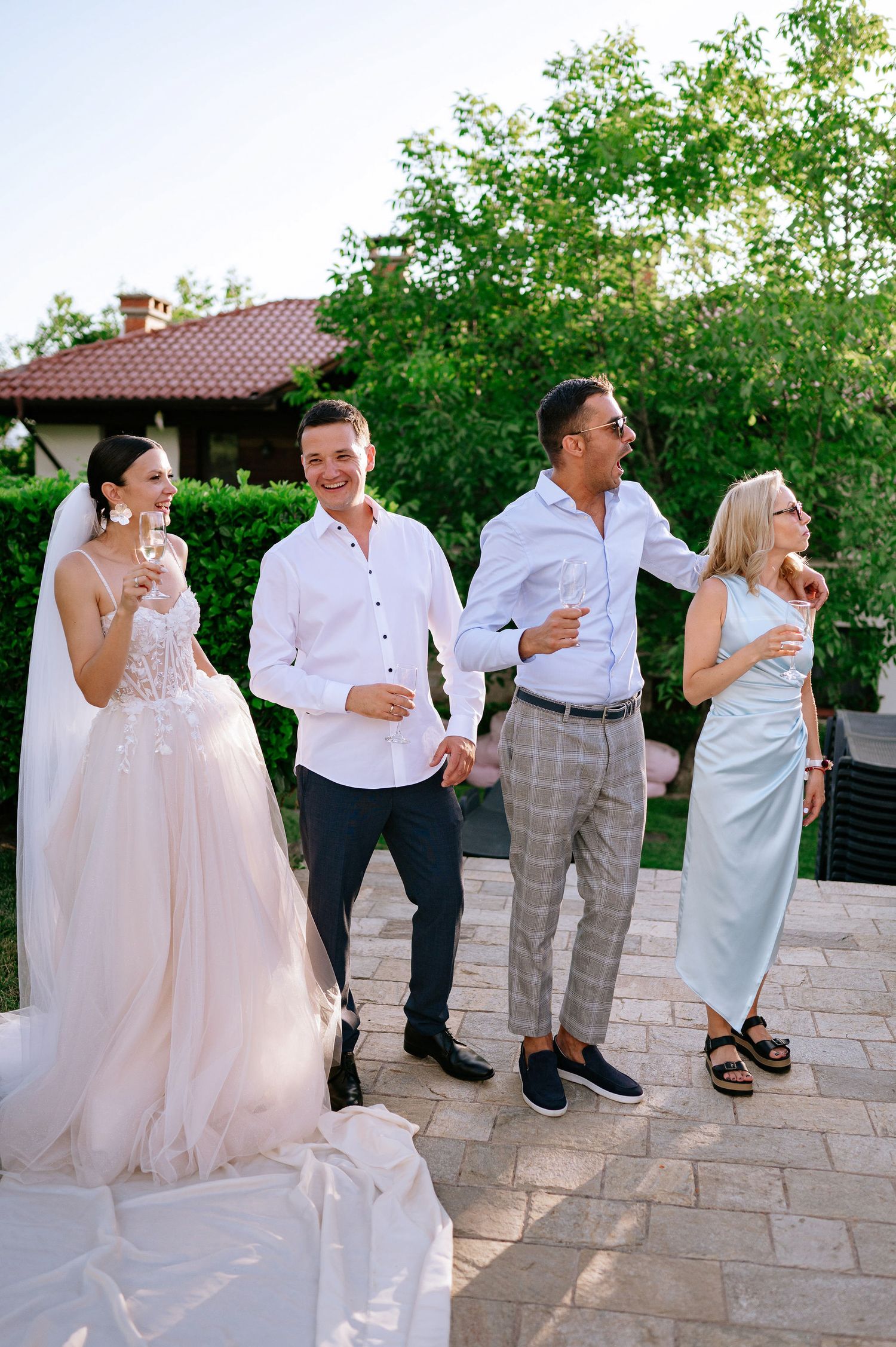 Wedding party enjoys drinks and conversation on outdoor stone patio.