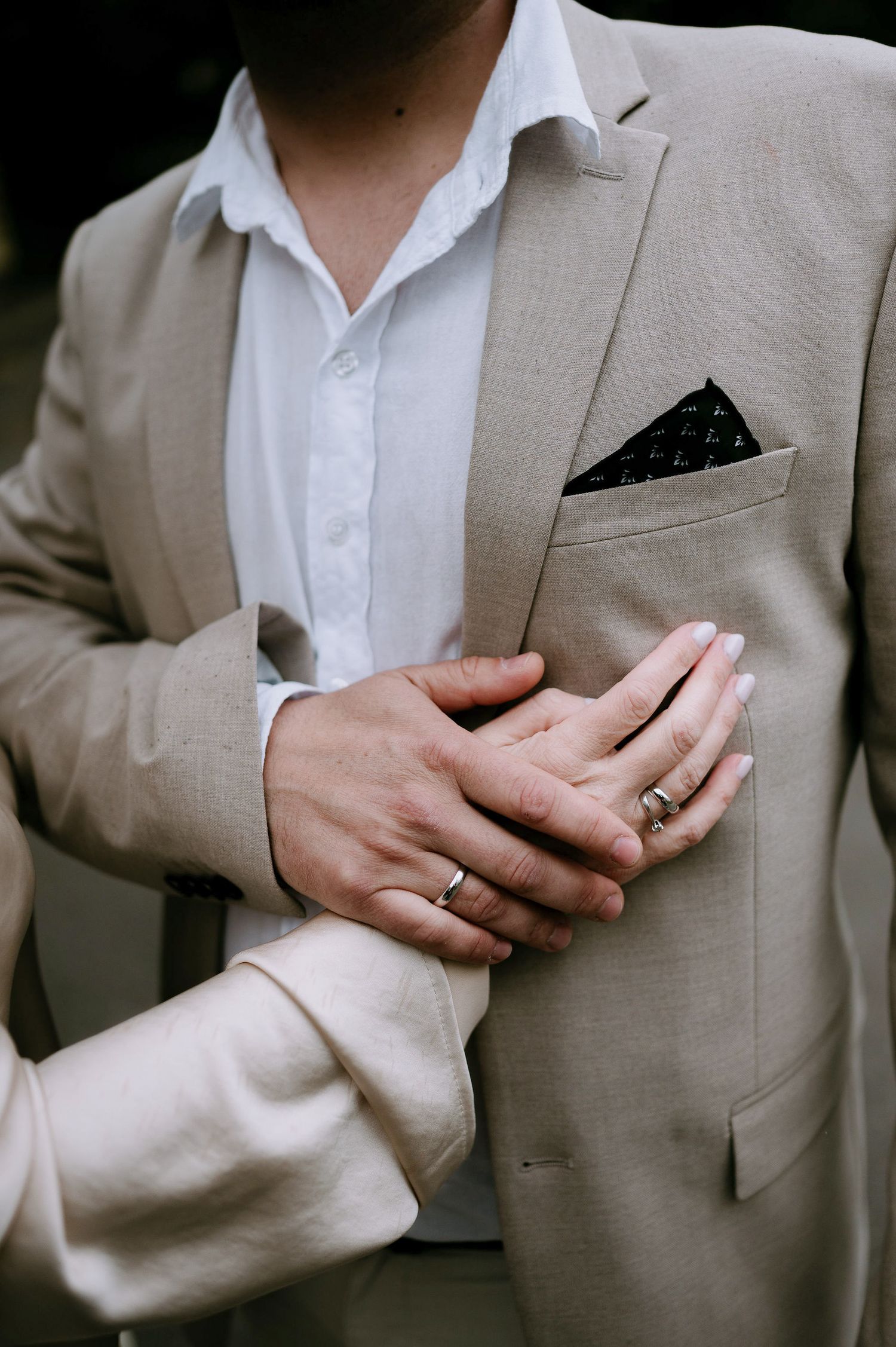 Detail shots of hands wearing rings and formal attire in beige tones.