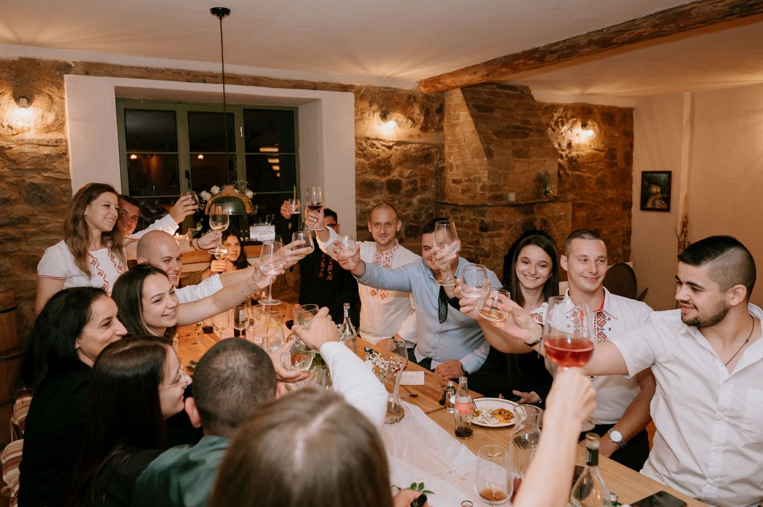 Large group toasting with drinks around a festive dinner table.