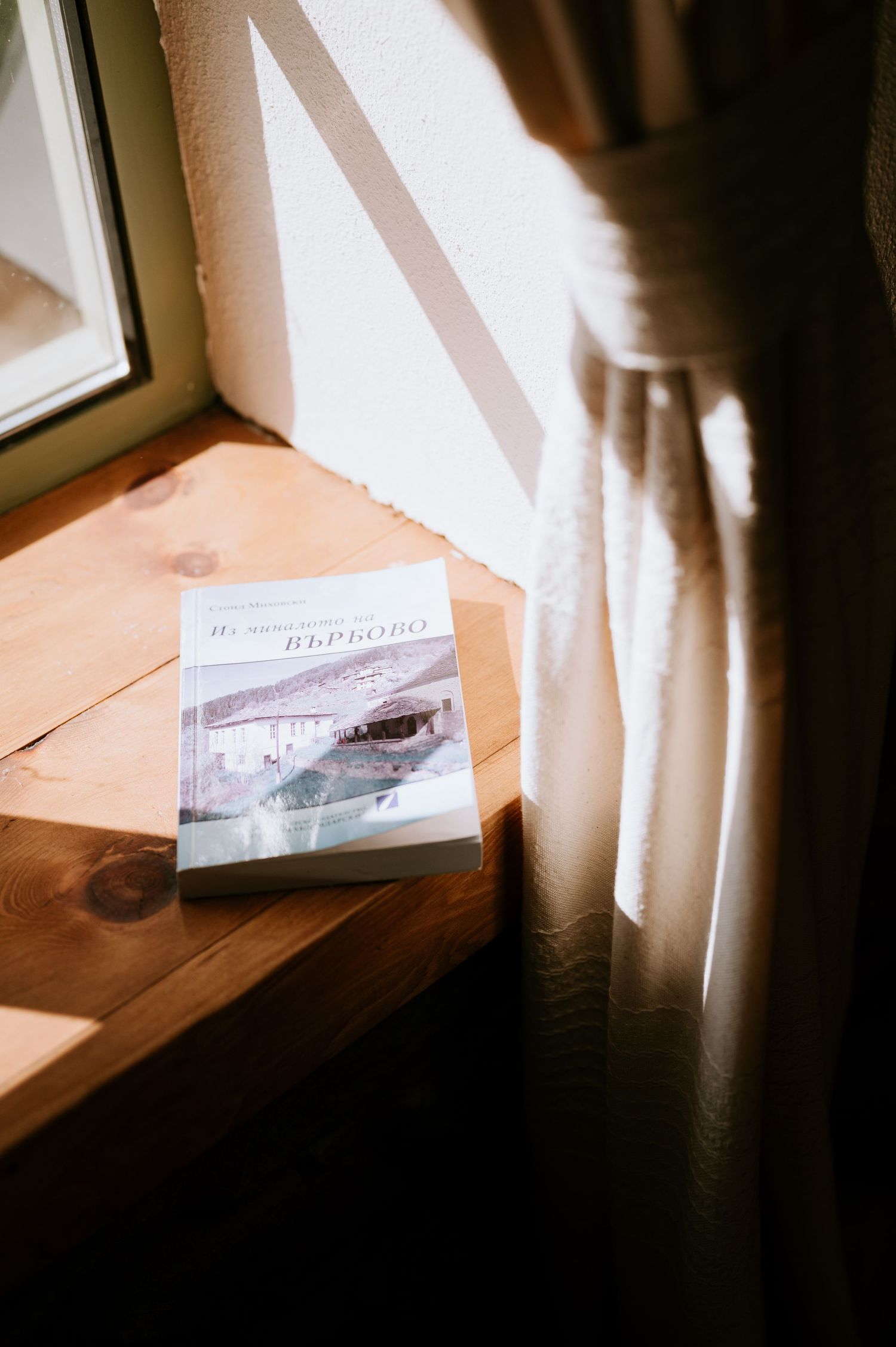 Sunlit window scene with papers or documents on wooden surface.