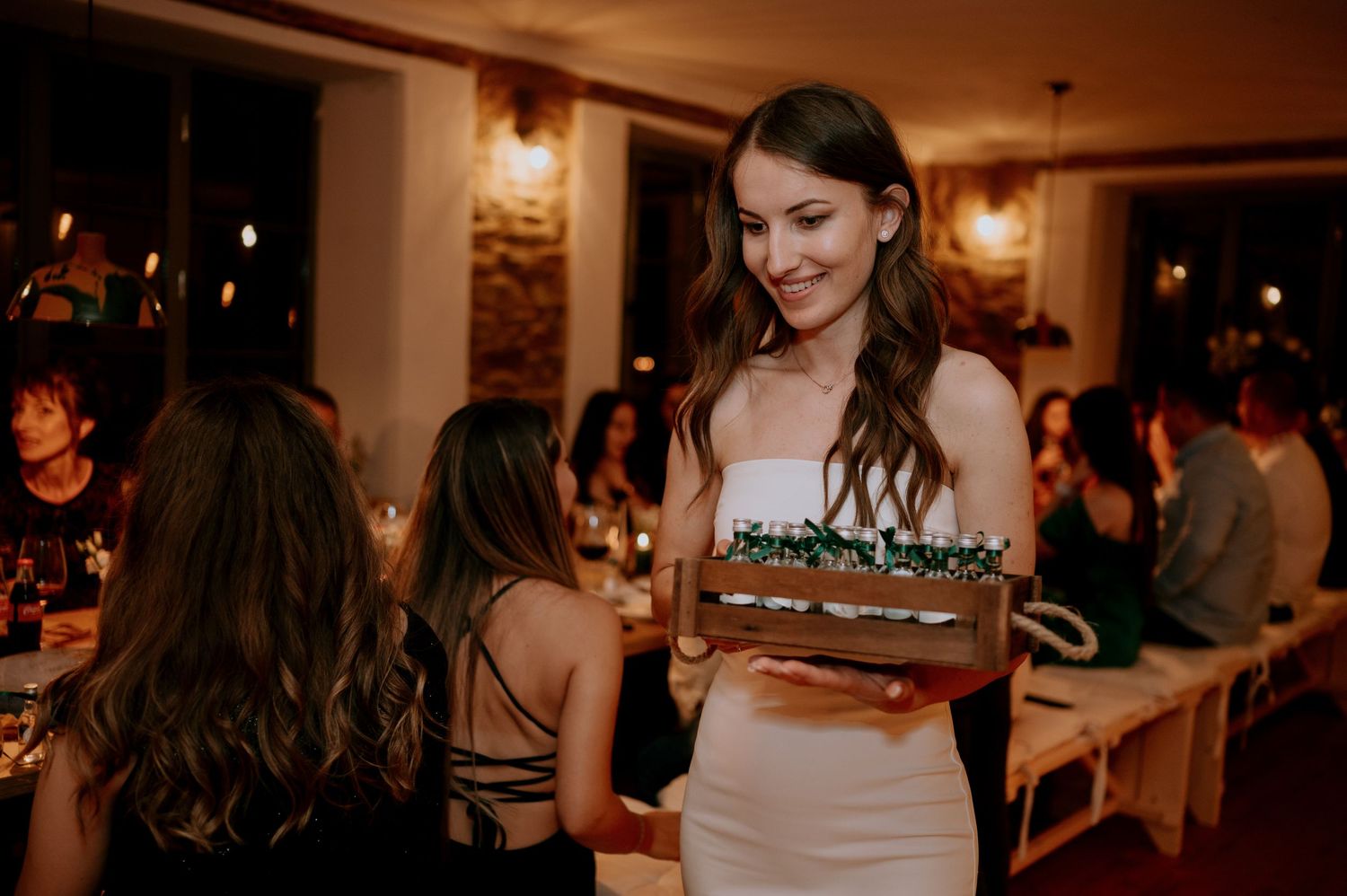 Evening celebration in a rustic venue with guests mingling at tables.