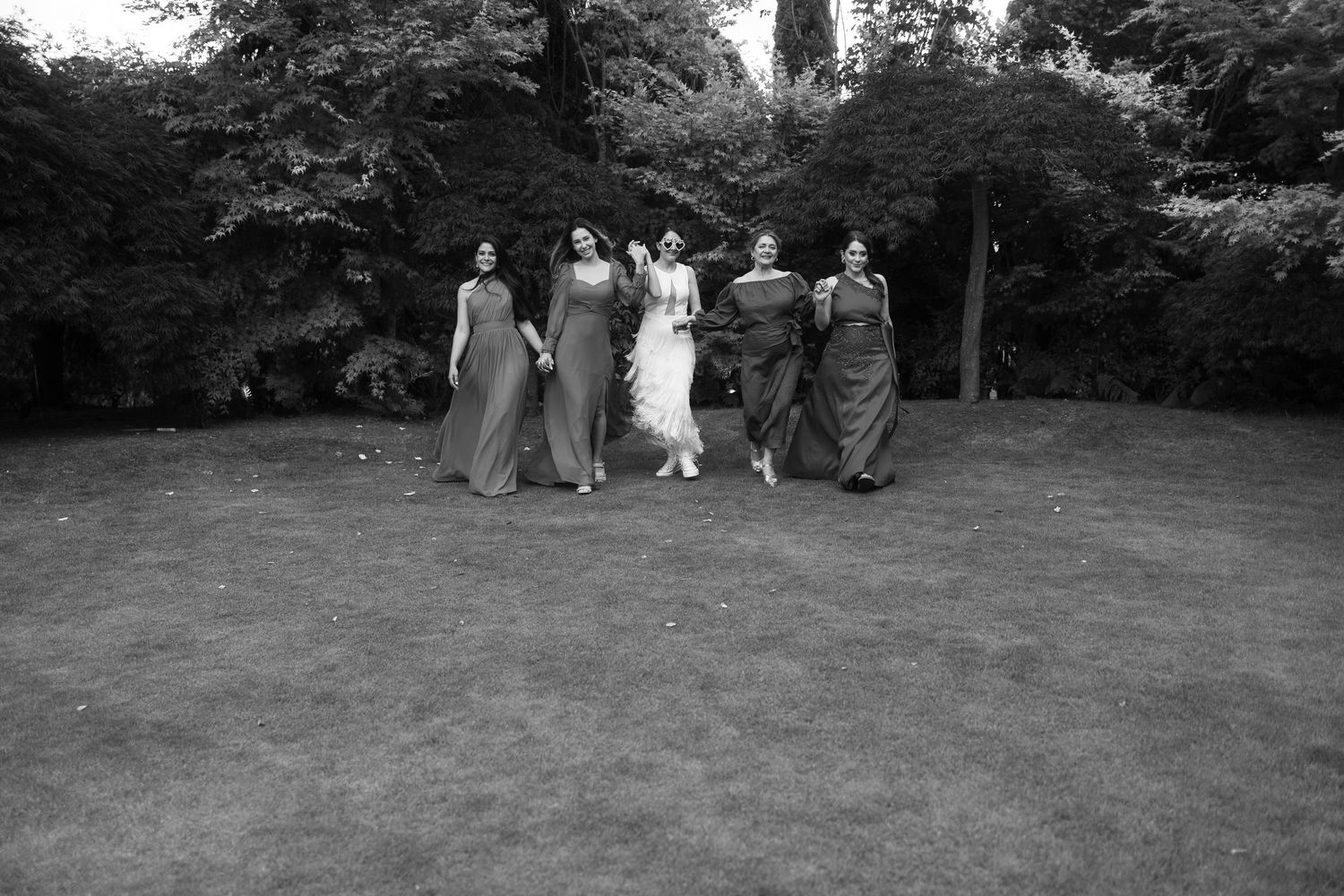 Wedding guests gather on a lush green lawn during an outdoor ceremony.