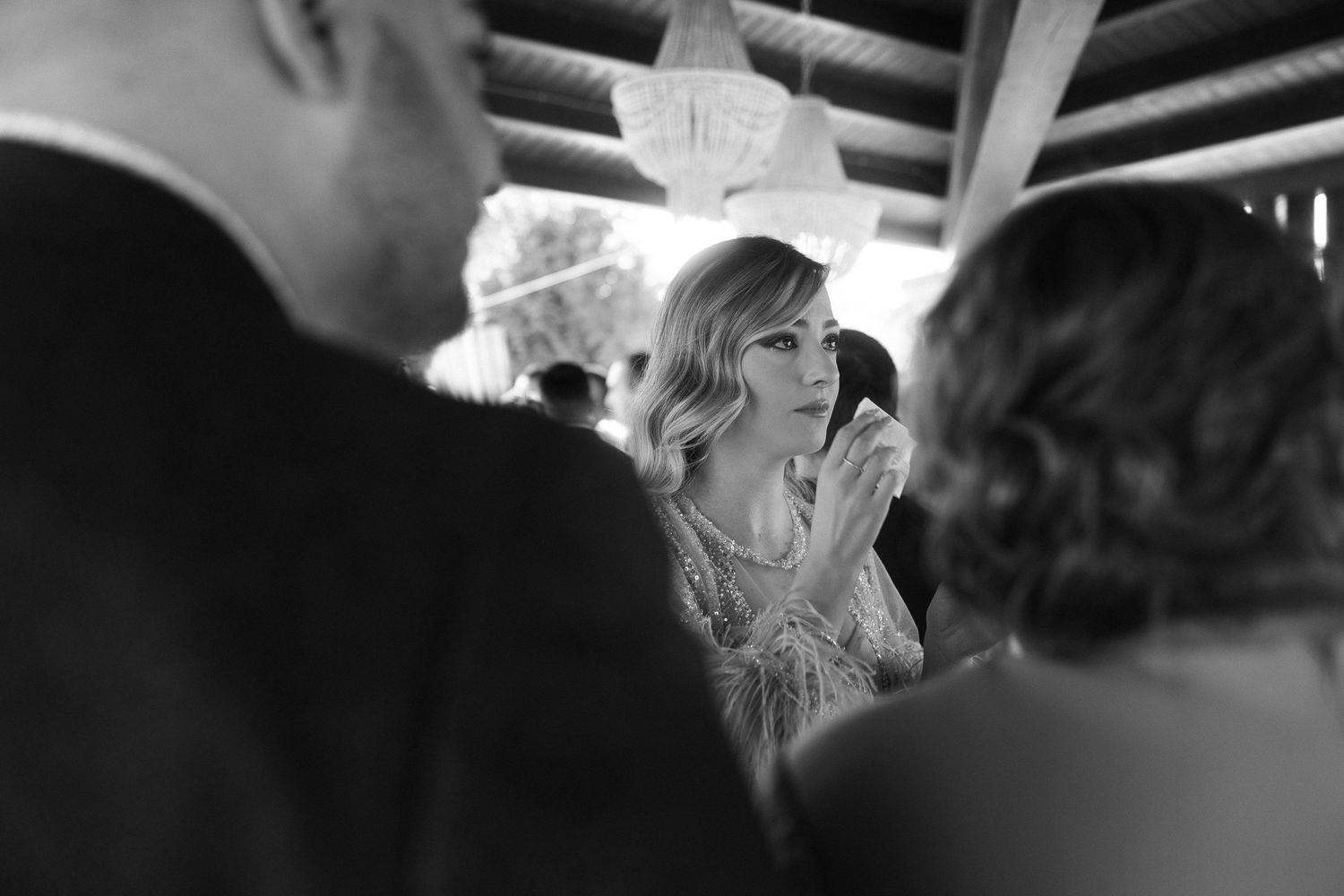 Invitada emocionada limpiándose las lágrimas durante la boda, fotografía en blanco y negro.