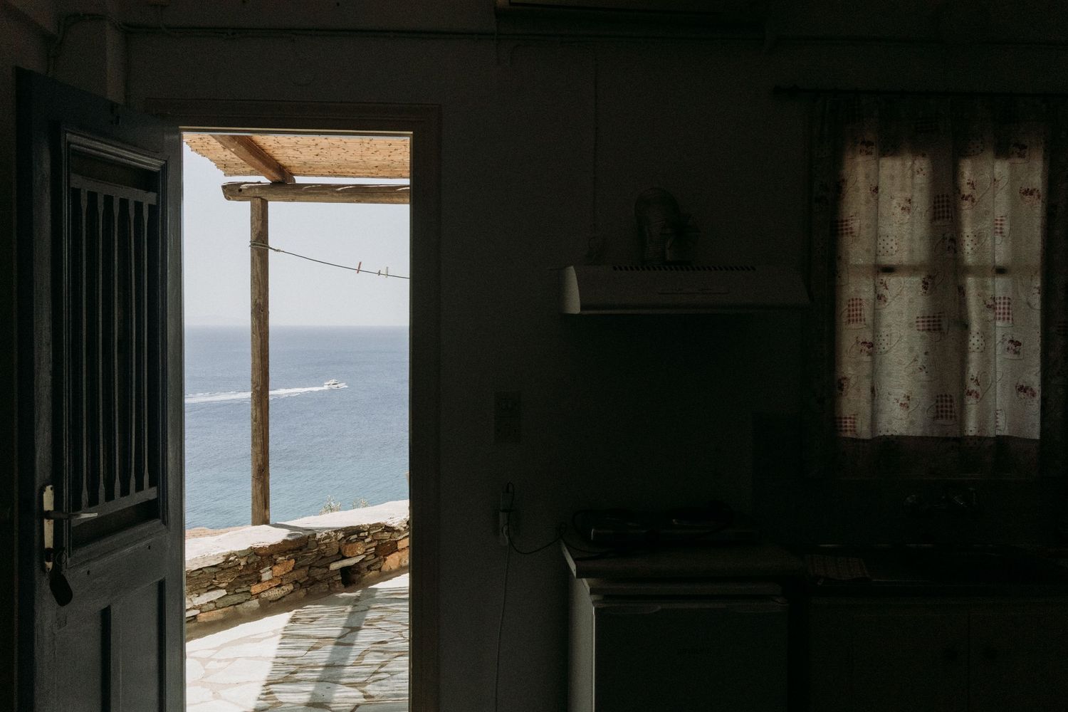 Dark interior hallway of an abandoned building with sunlight streaming through windows overlooking an ocean view.