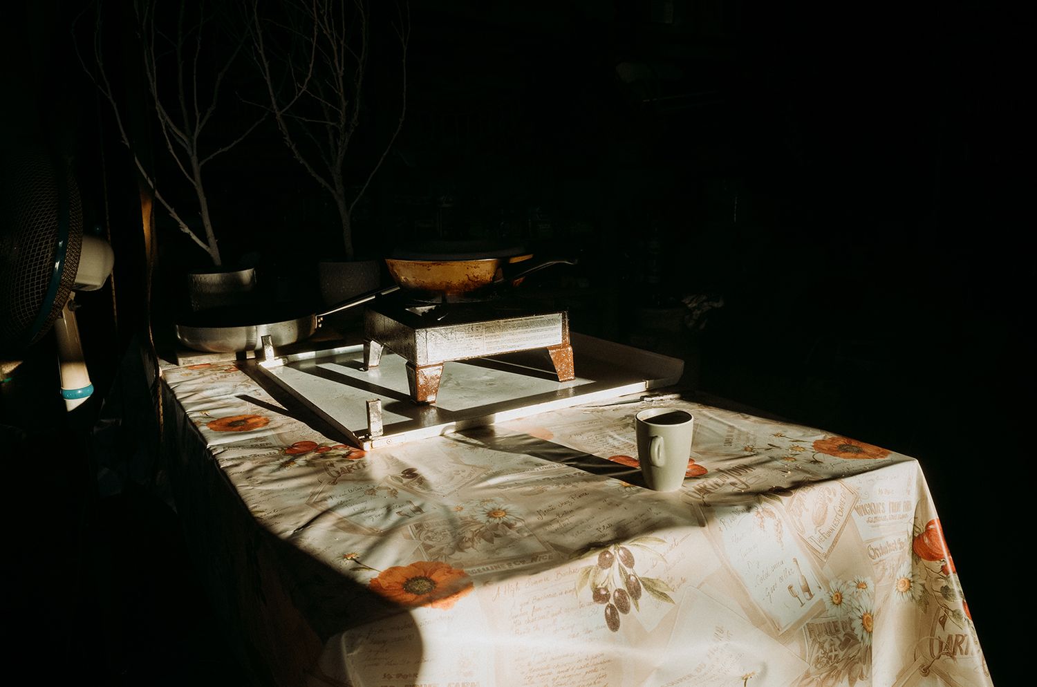 A dark wooden table illuminated by natural light through a window shows scattered papers and documents.