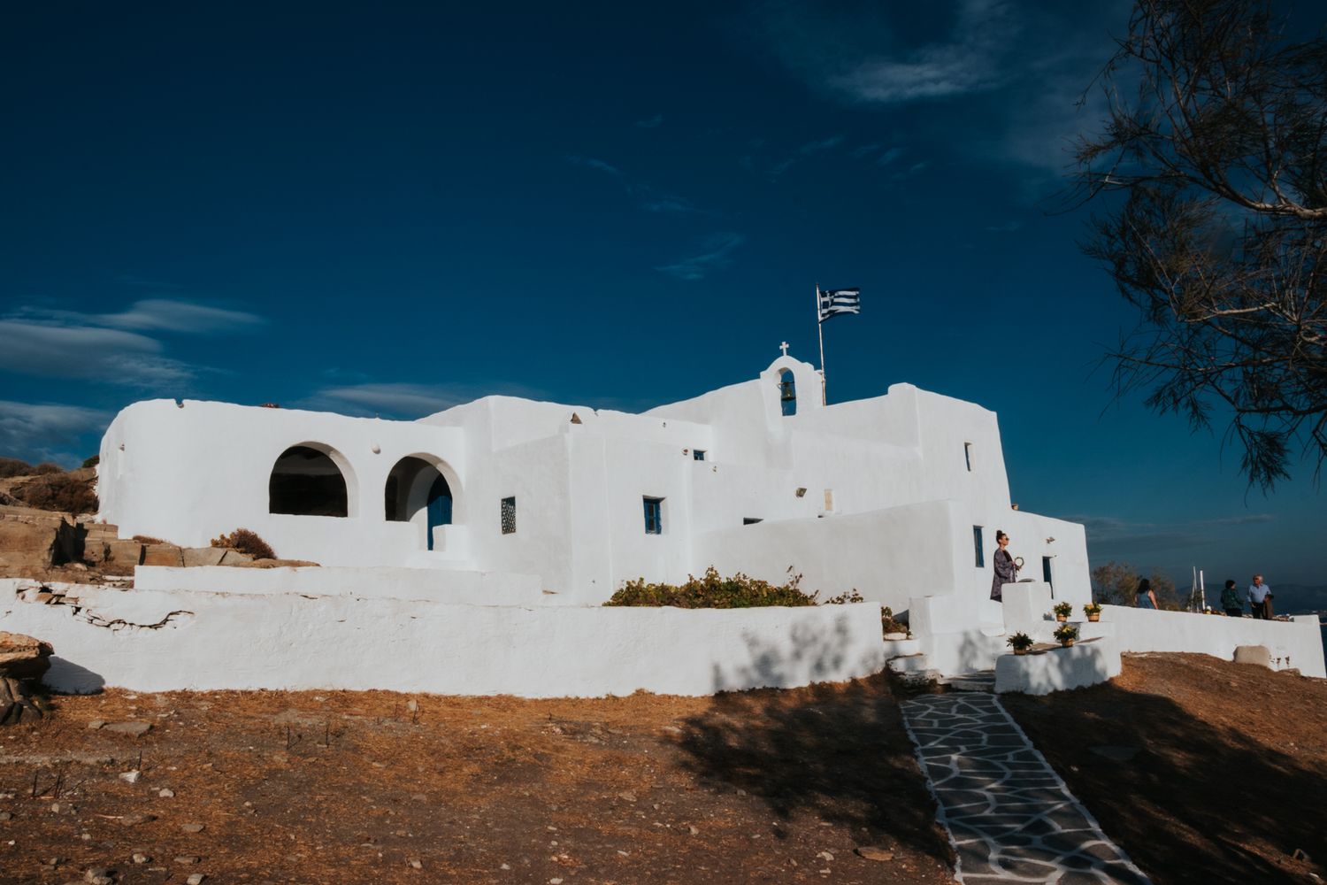 White Mediterranean architecture against deep blue sky with traditional stone walls and pathways.