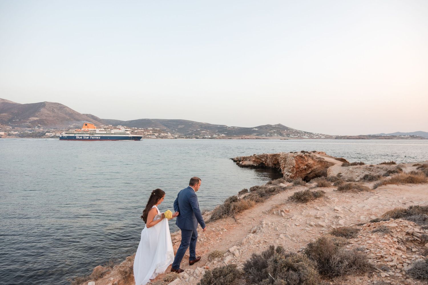 Coastal wedding photography session with rocky shoreline and ferry boat in background.