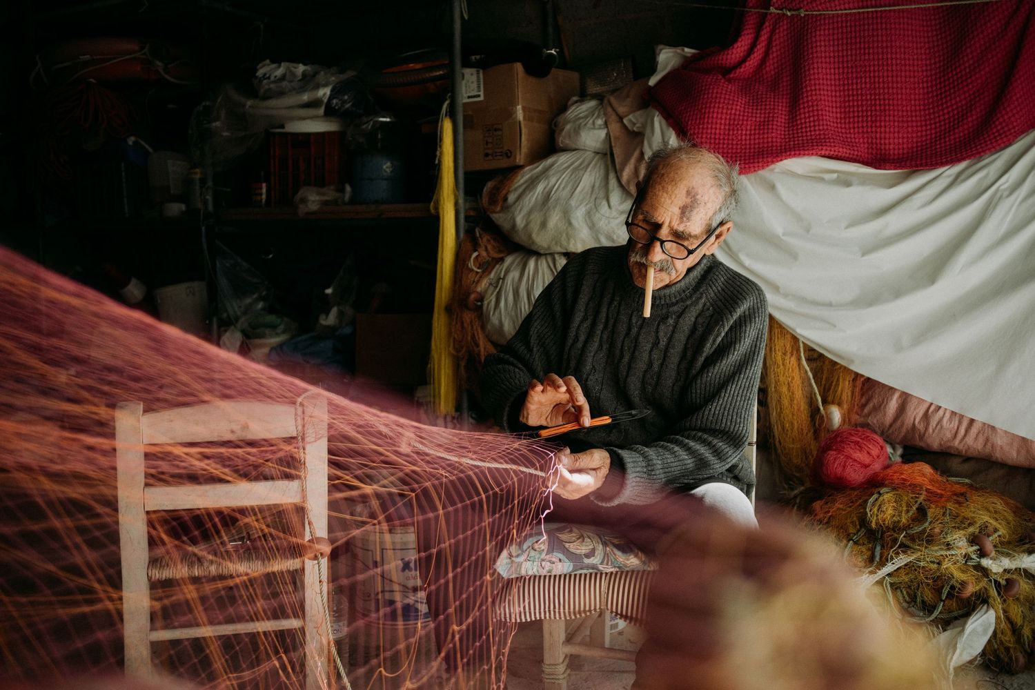Artisan weaving traditional textiles on wooden loom with red and natural fibers.