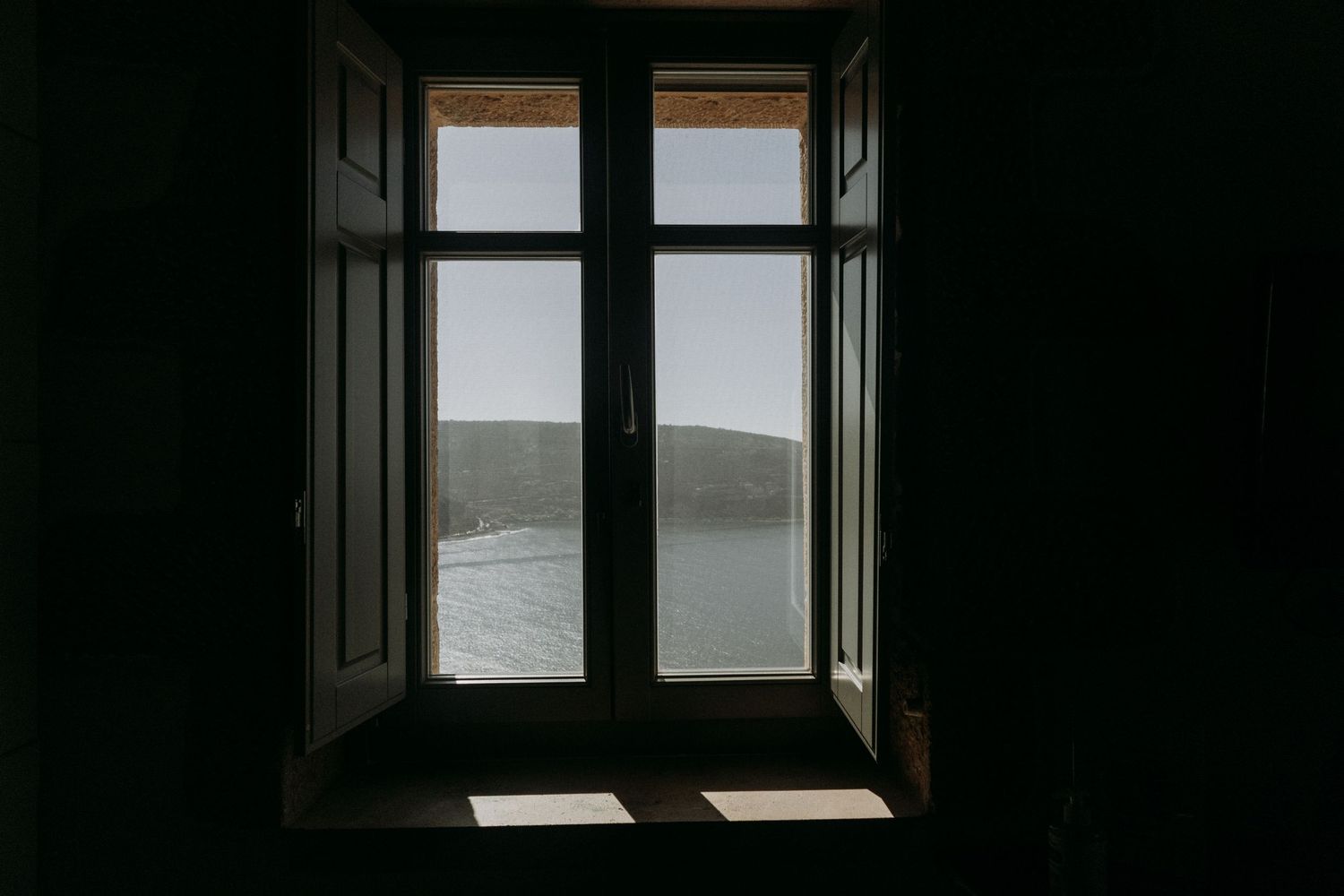 Series of window frames viewed from dark interior showing bright outdoor scenes.
