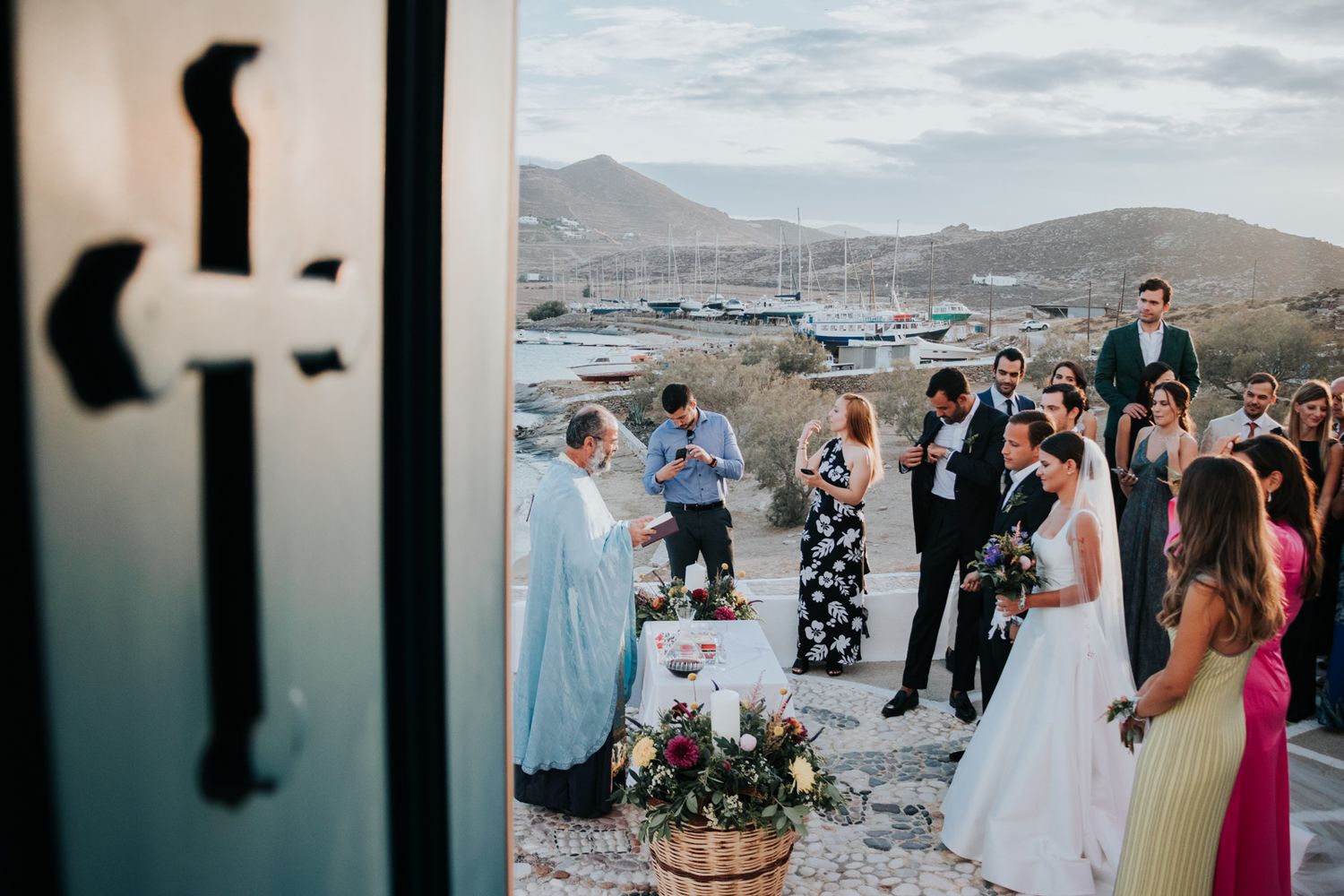 Outdoor wedding ceremony overlooking a scenic marina with mountains in the background.